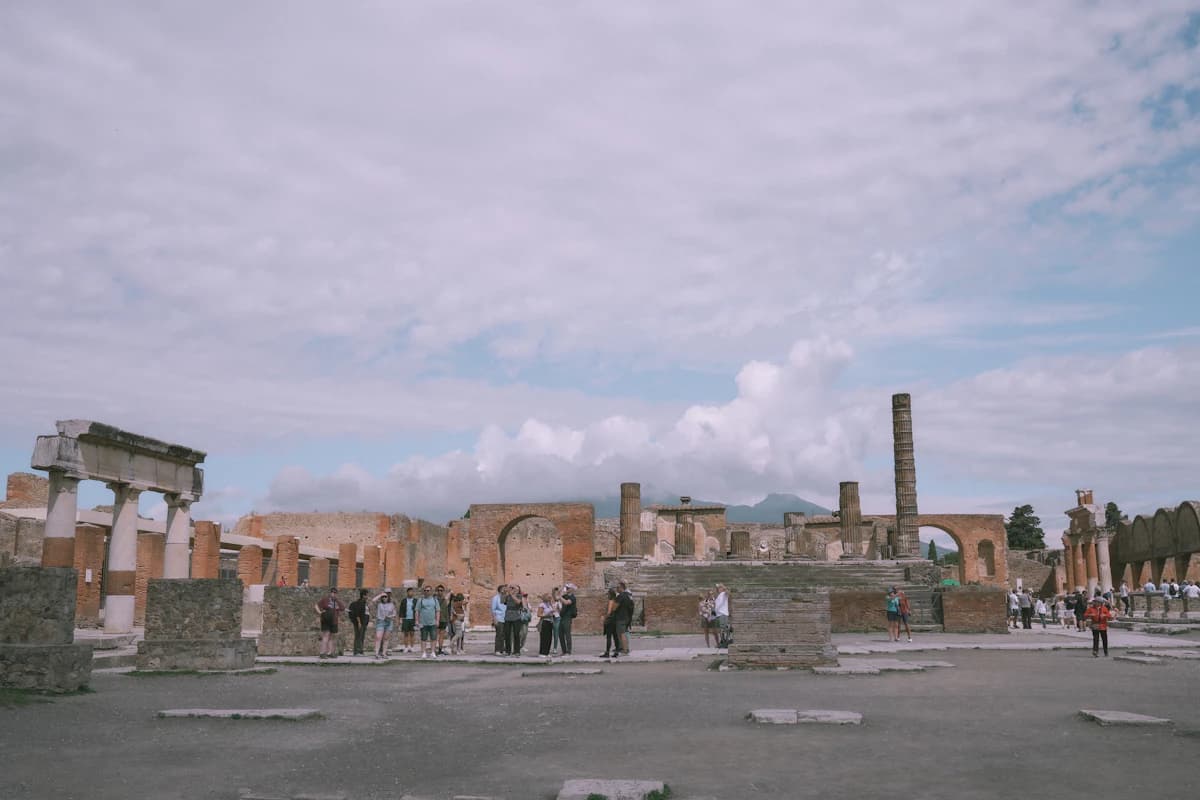 Ancient roman ruins with scattered tourists under cloudy sky