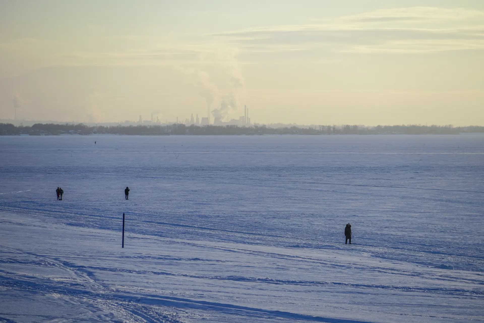 a couple of people walking across a snow covered field