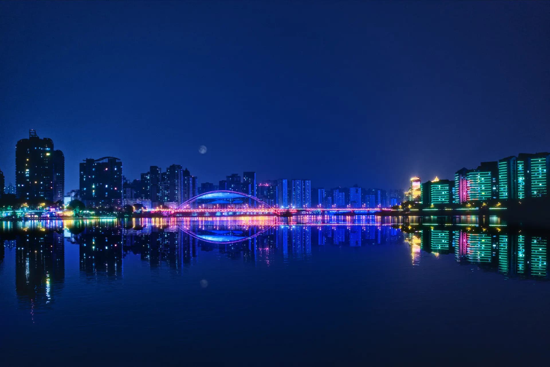 City skyline with bridge reflected in water at night
