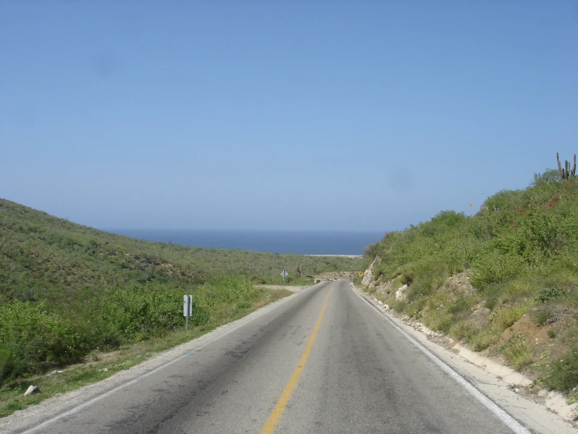 an empty road with a view of the ocean in the distance