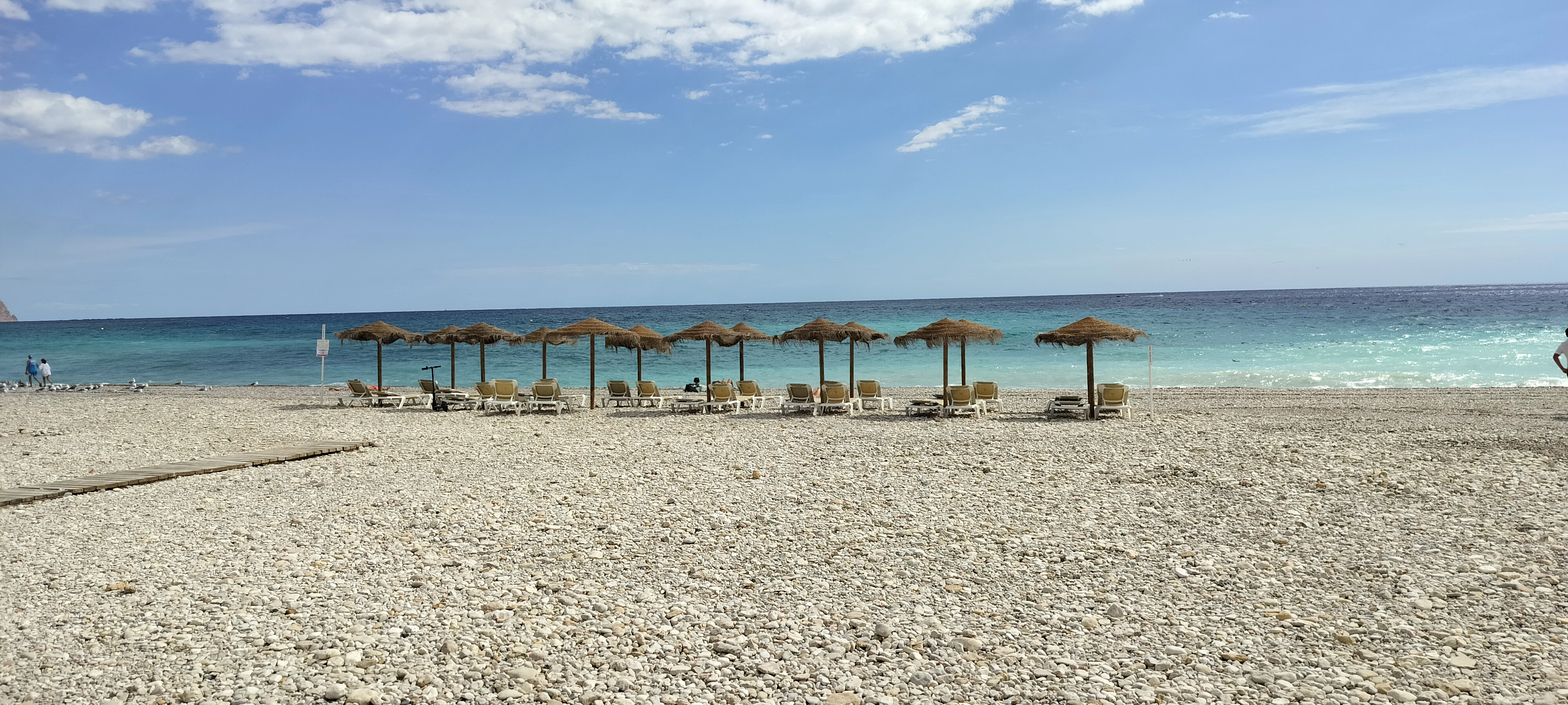 Beach with umbrellas and lounge chairs by the ocean.