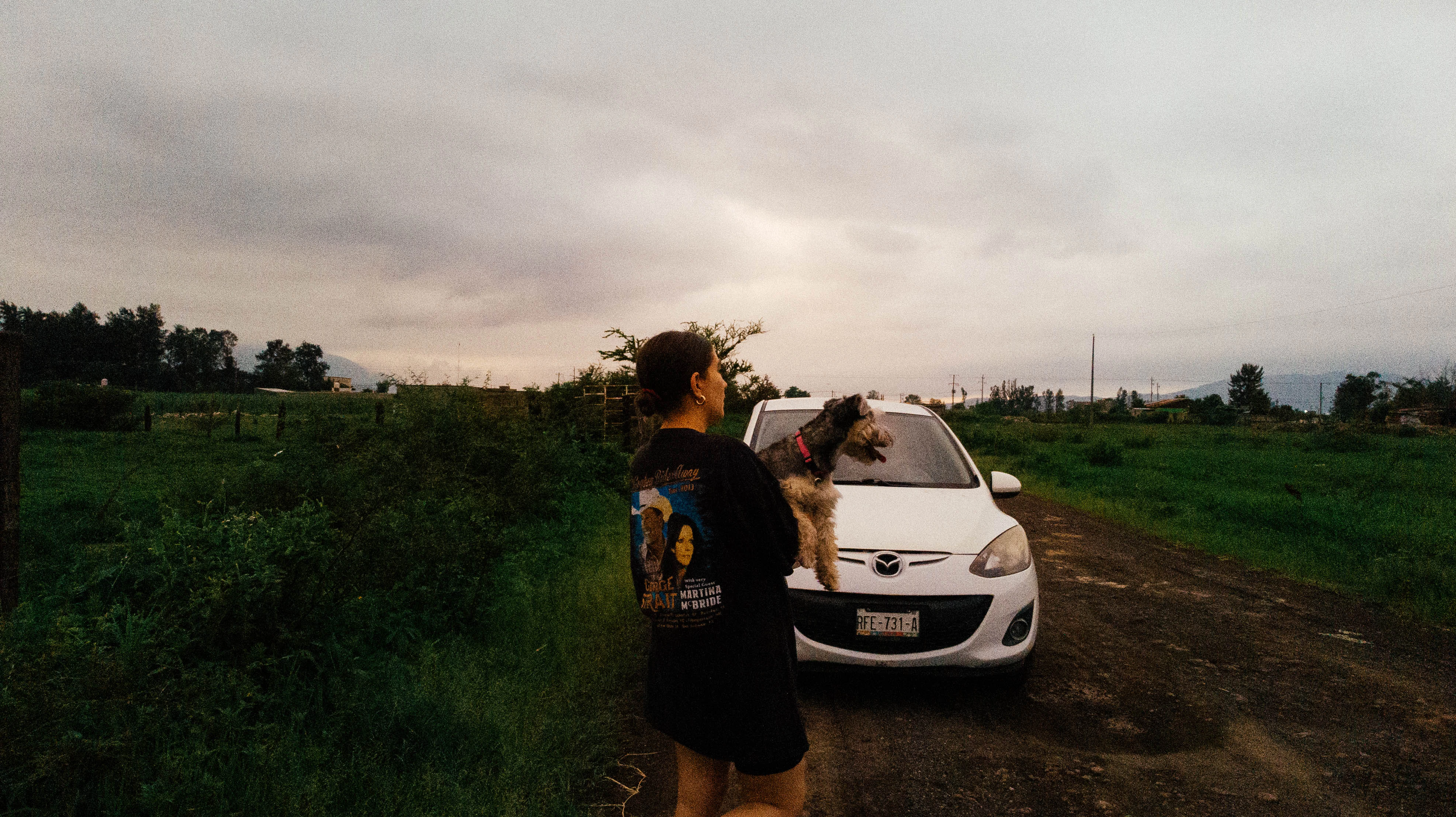 a person standing next to a white car on a dirt road