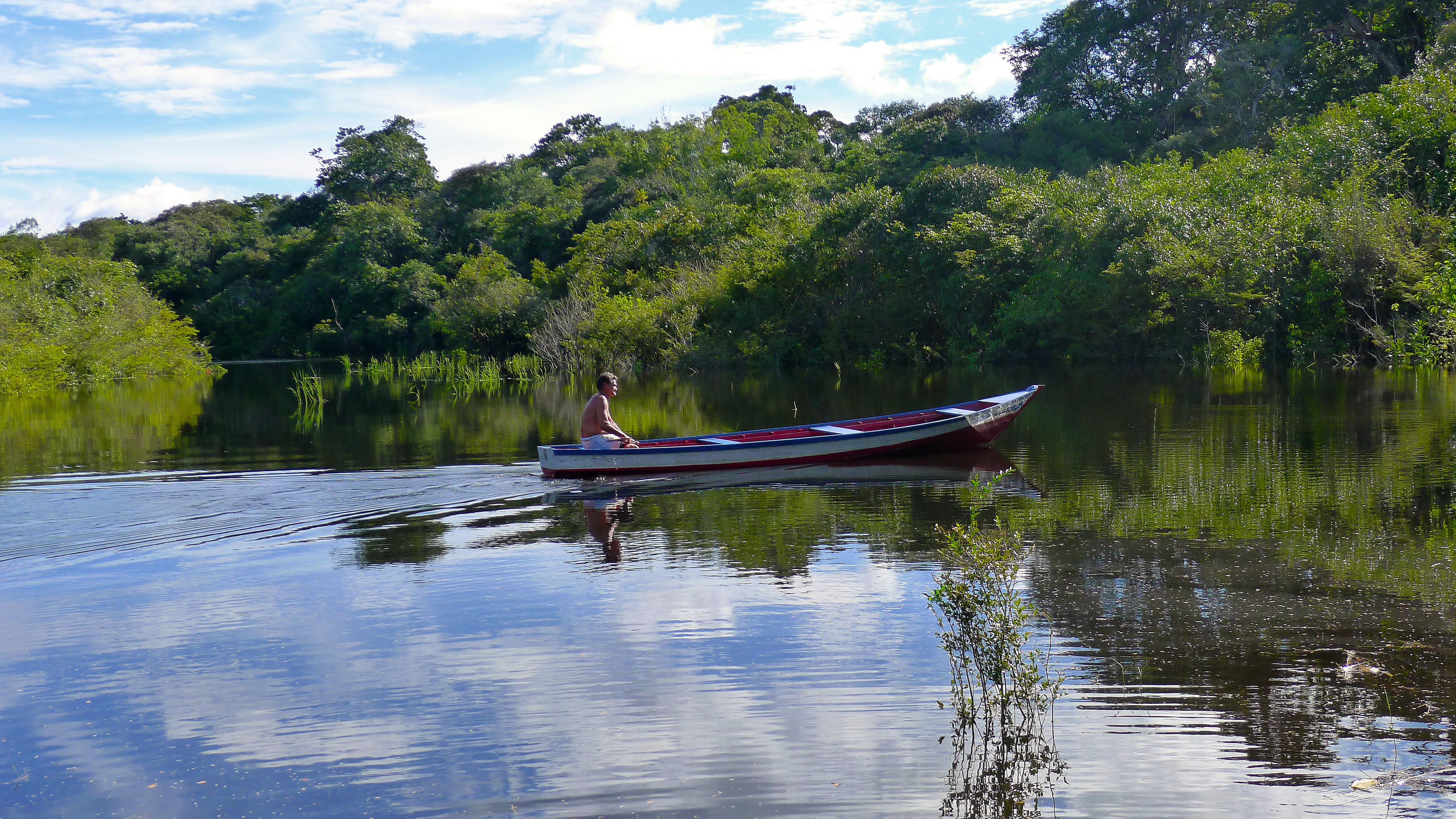 a man in a red and white boat on a river