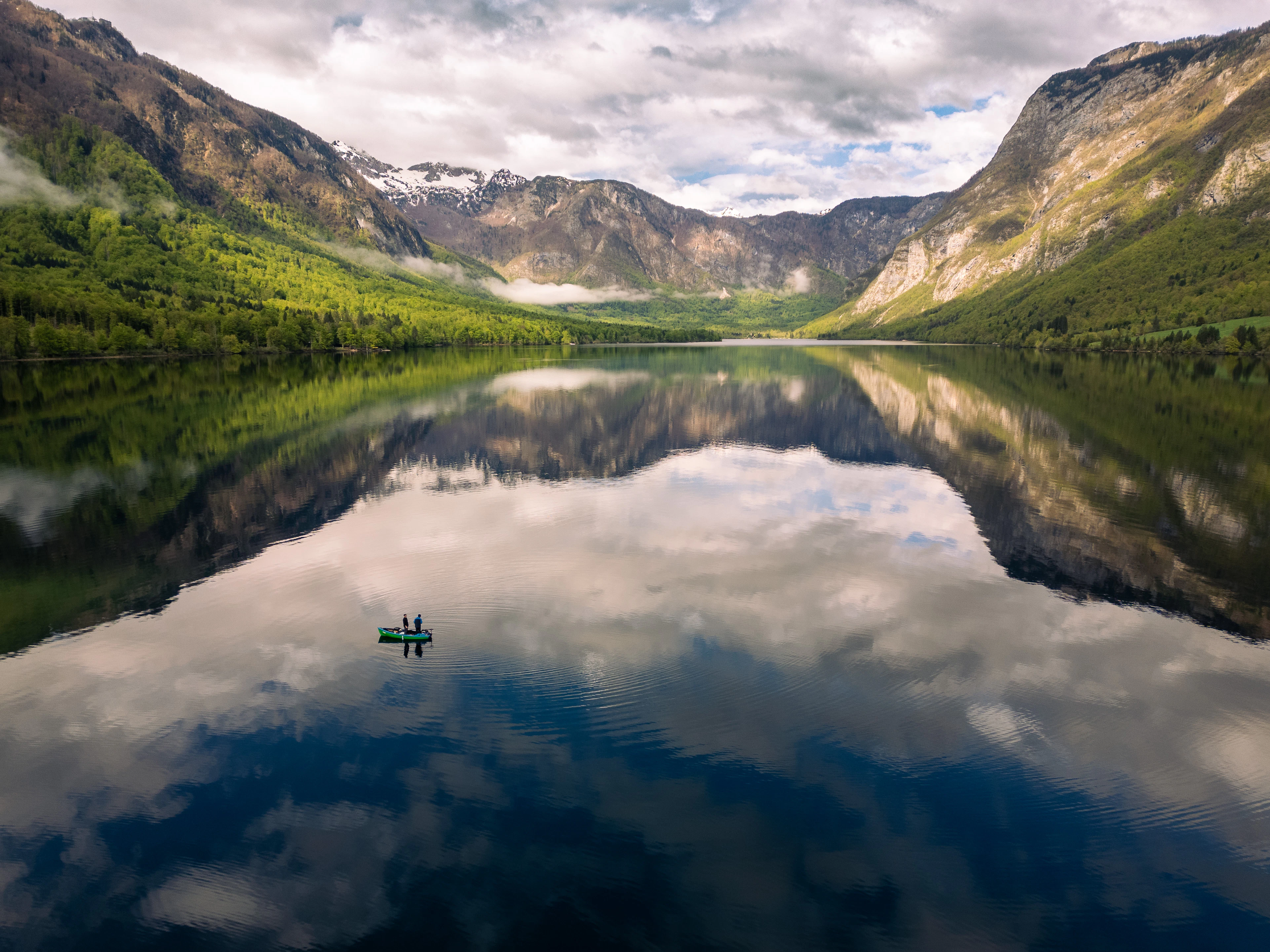 A small boat on a calm lake reflecting mountains
