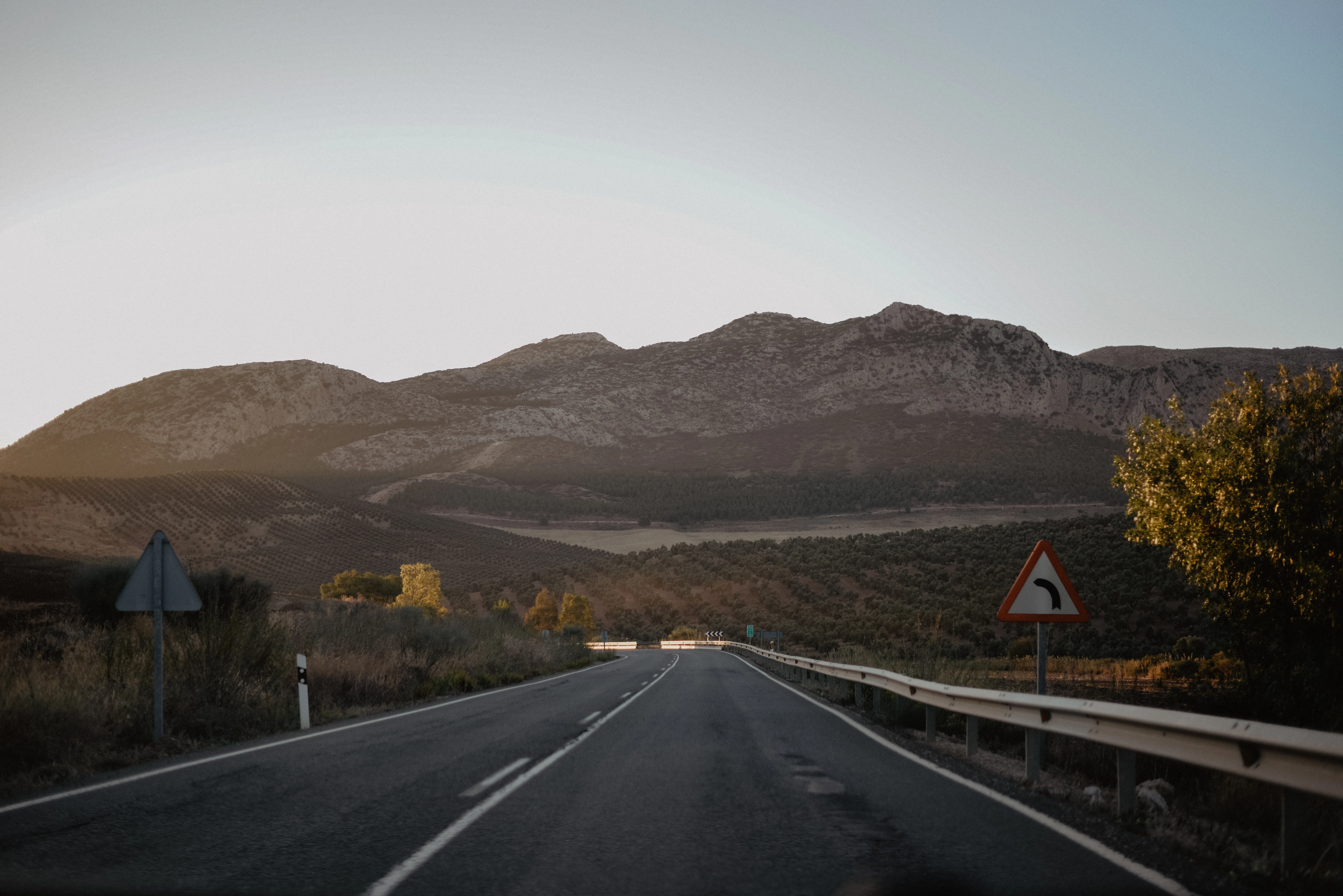 black asphalt road near brown mountain during daytime