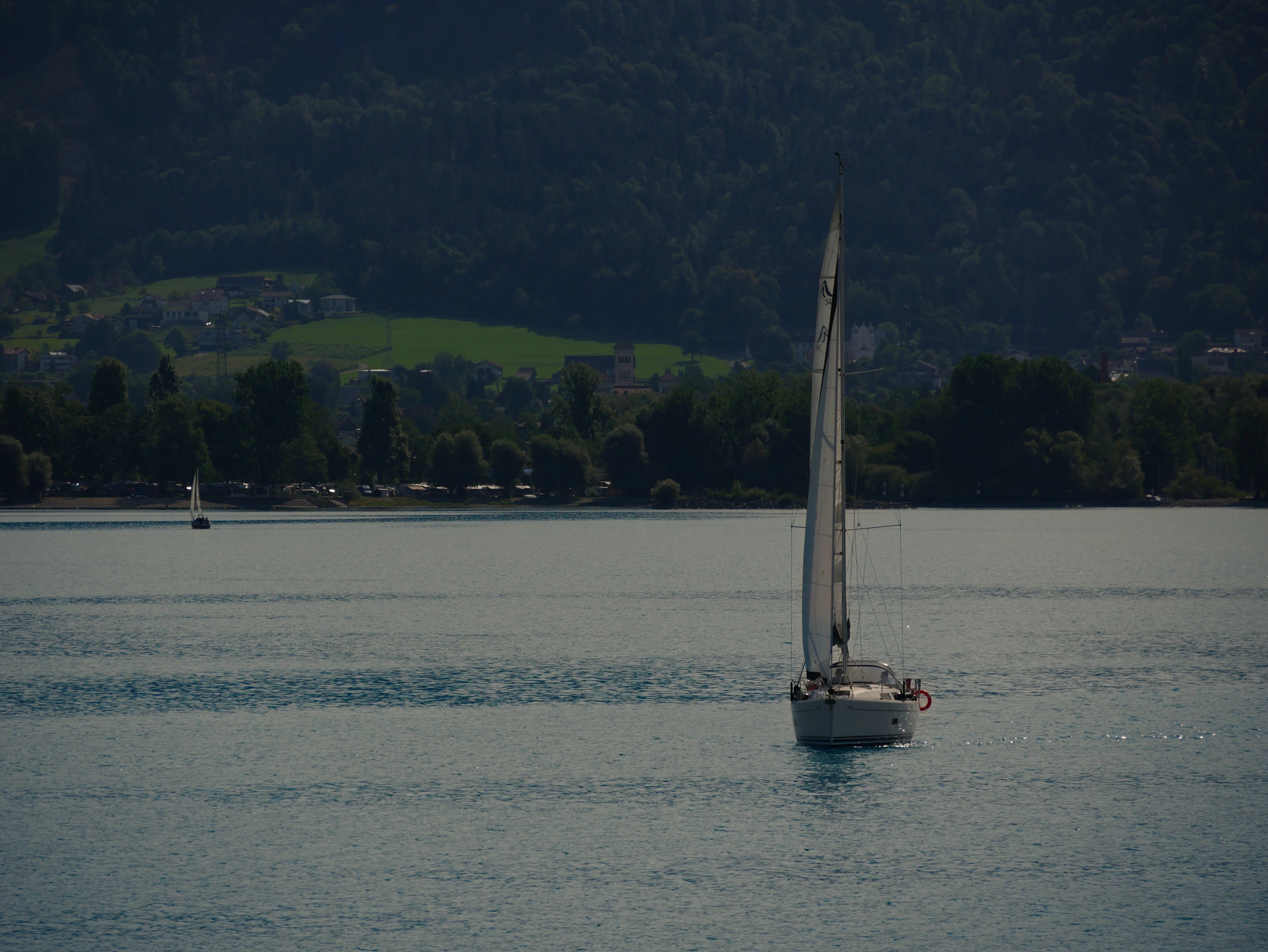 Sailboat on a calm lake with forested hills background