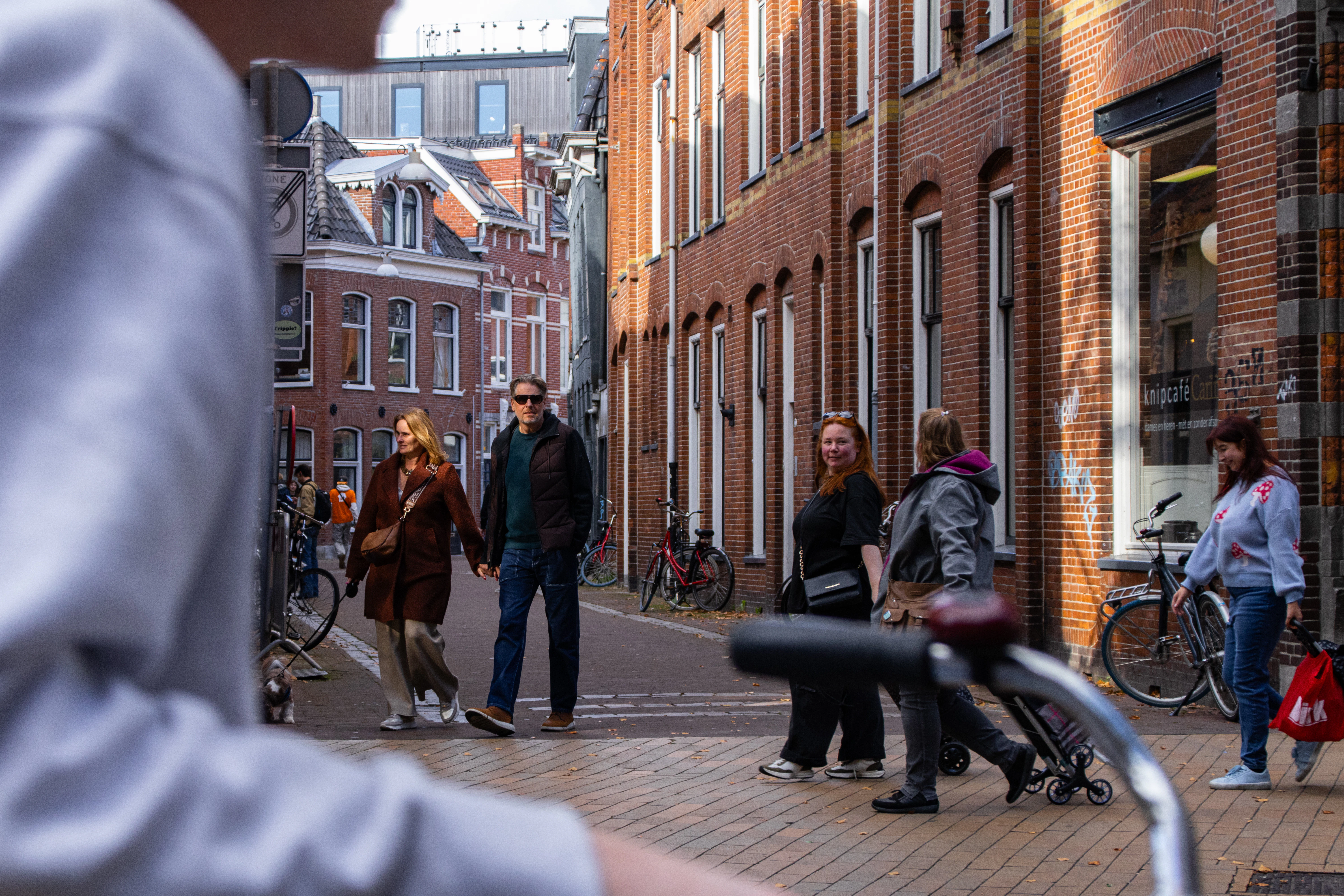 A group of people walking down a street next to tall buildings
