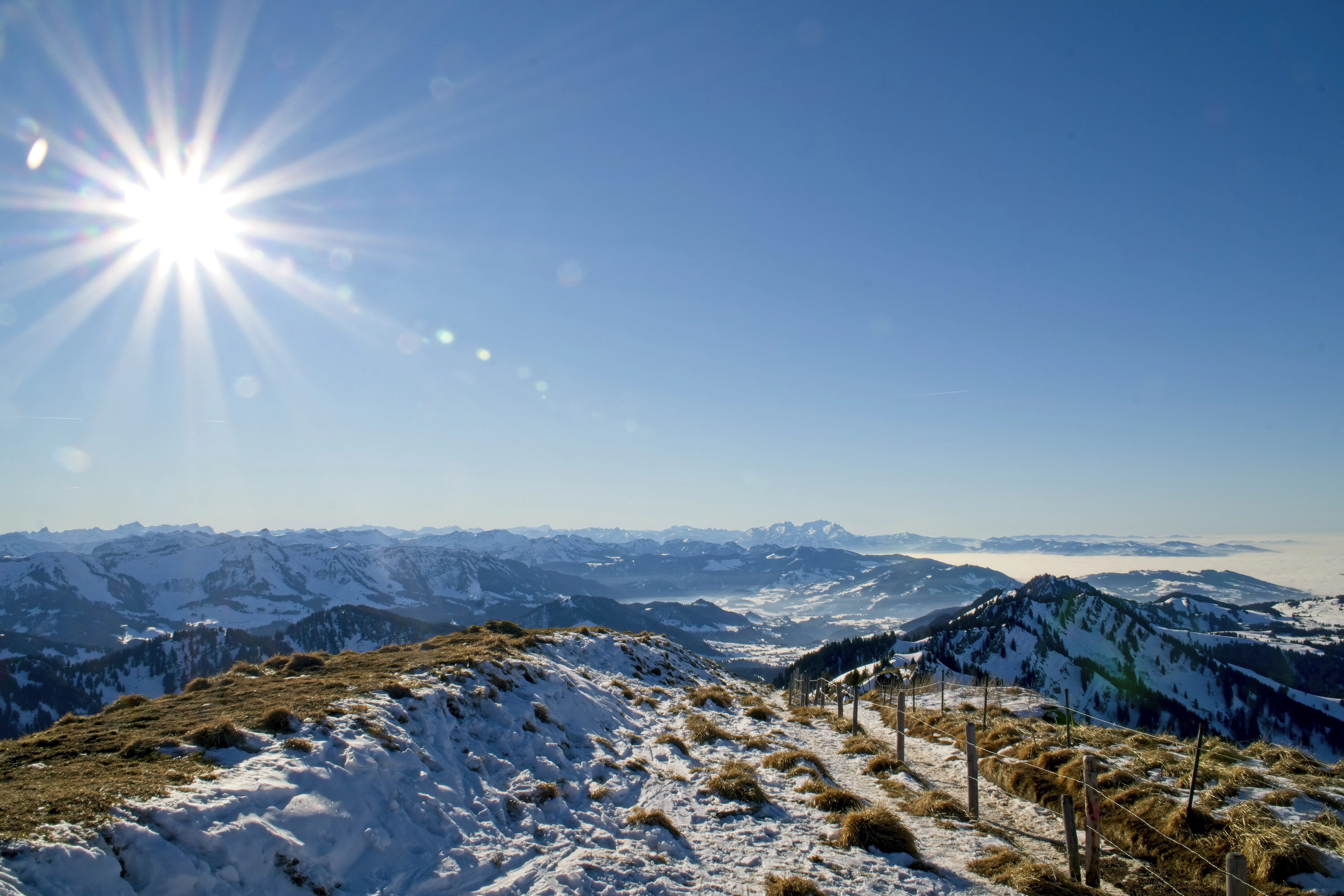 Bright sun shines over snowy mountain landscape.