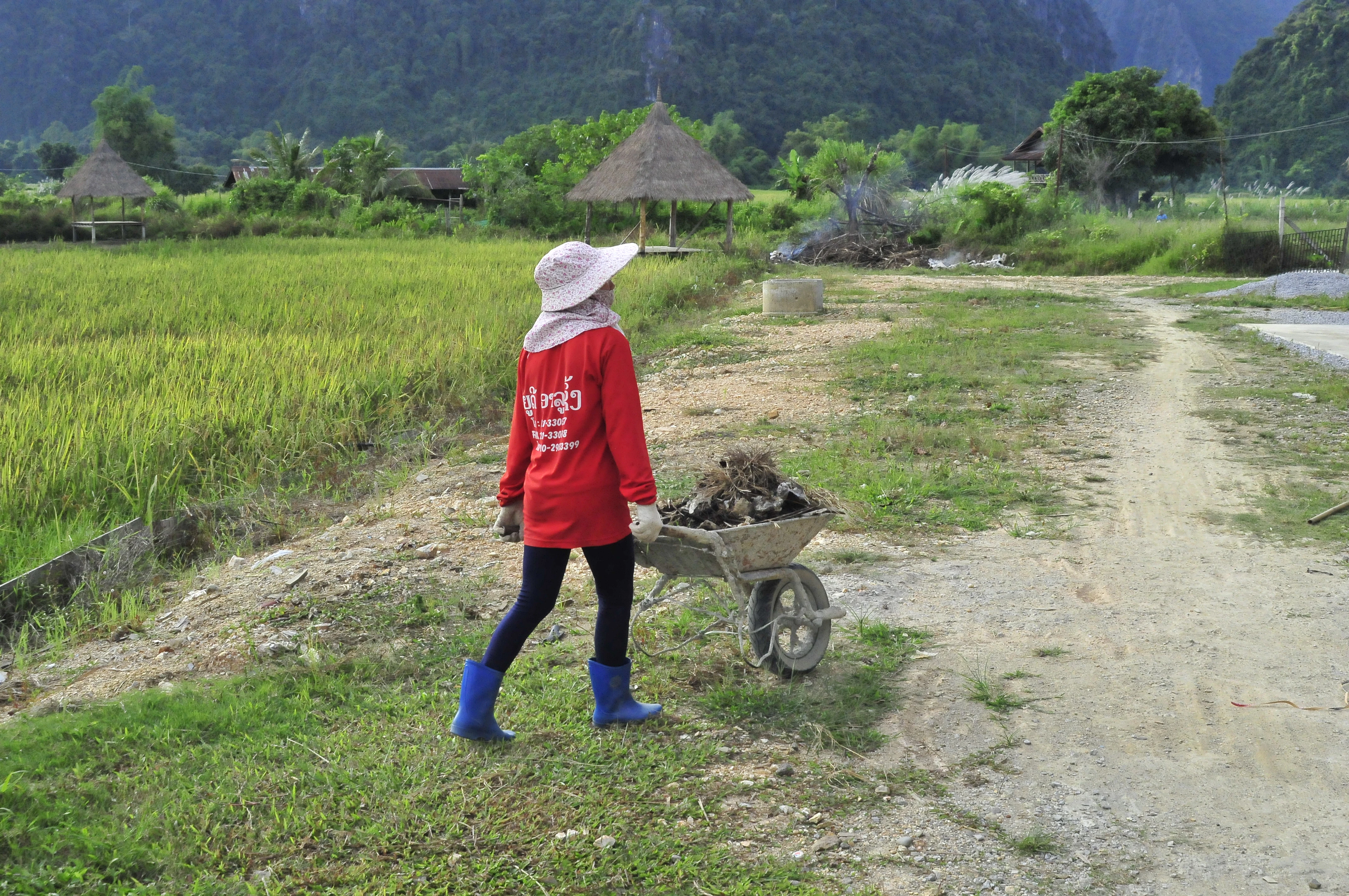 Person pushing a wheelbarrow on a dirt path