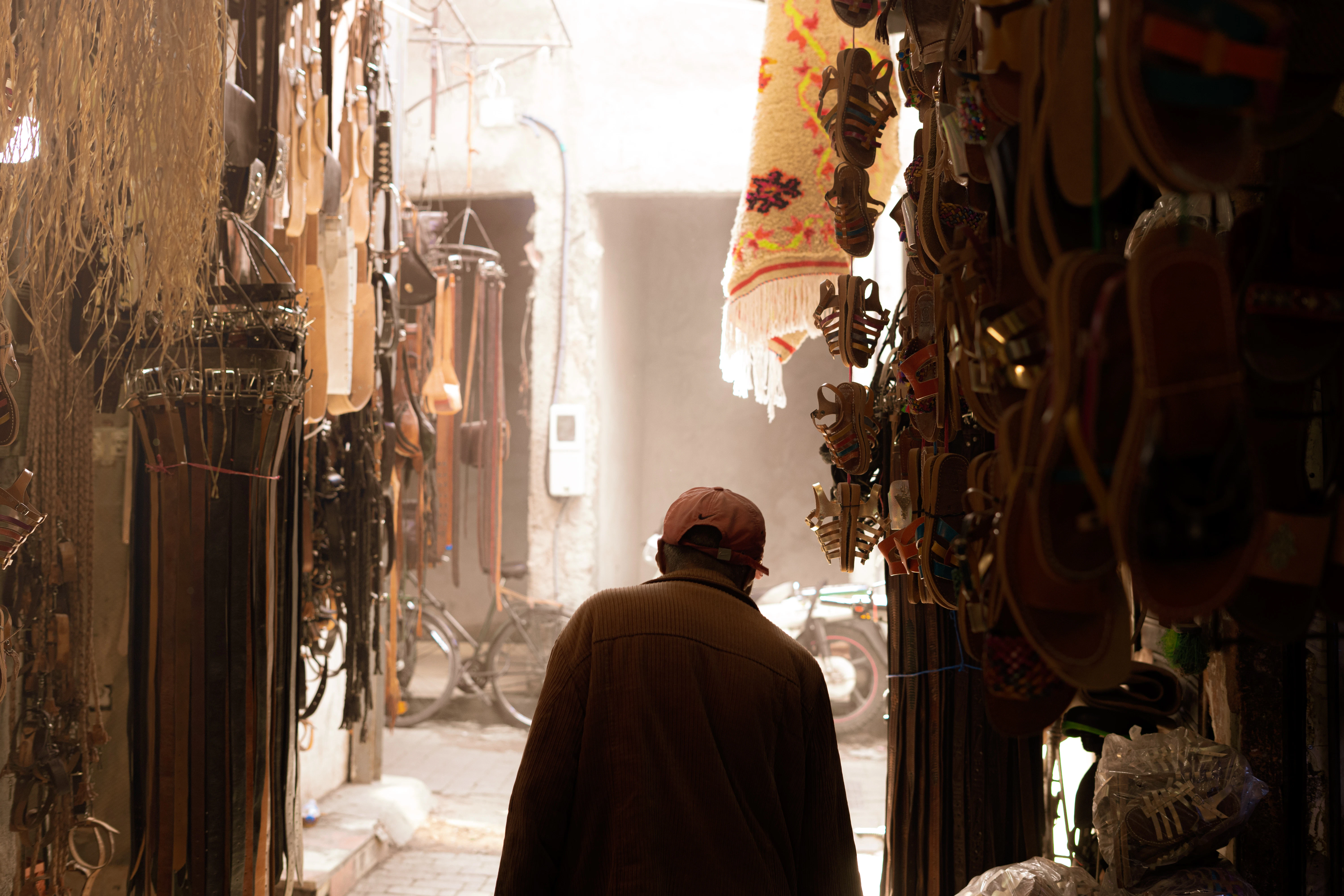 Man walks through a narrow market alley.