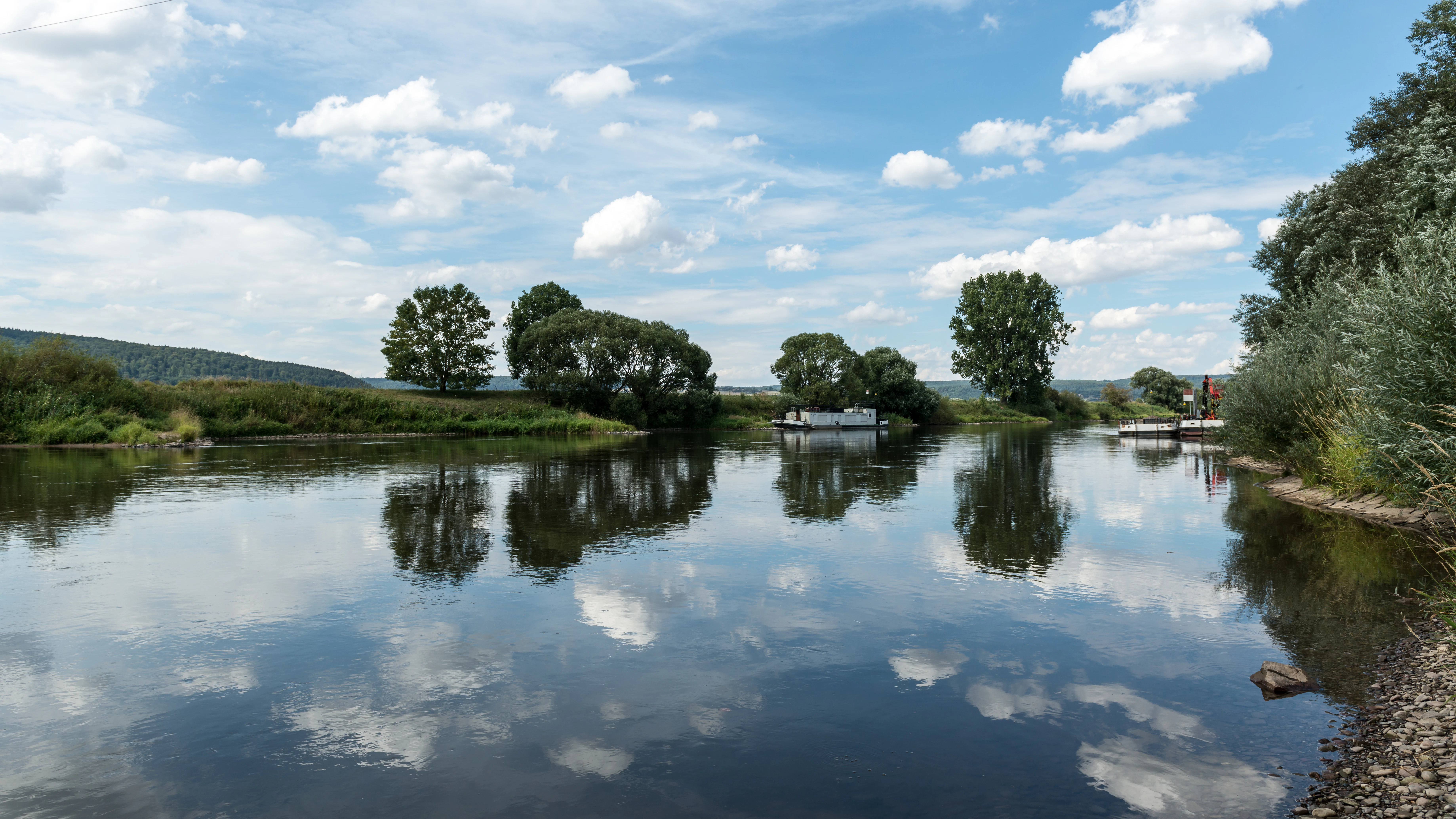 A body of water surrounded by trees and clouds