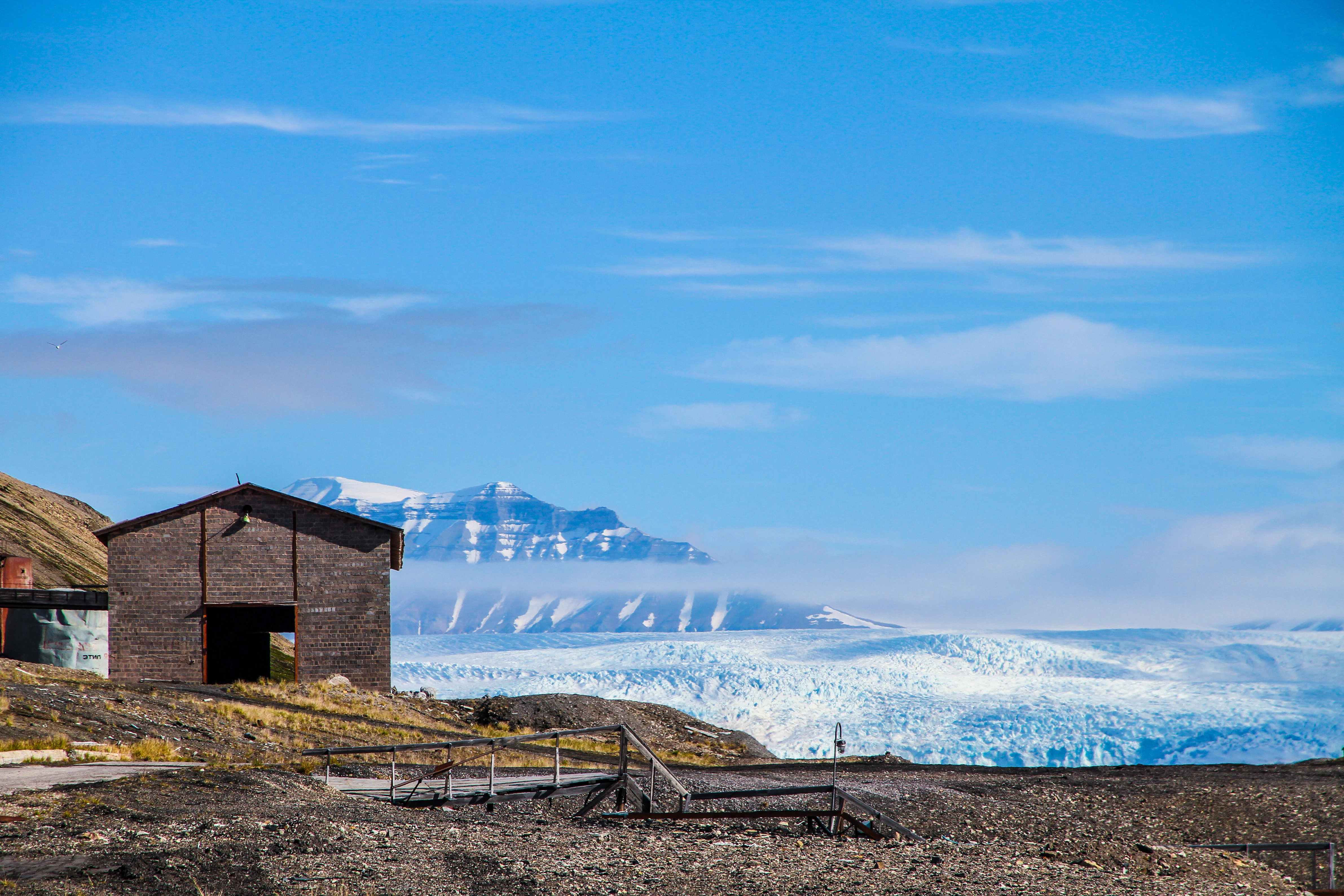 gray wooden shed overlooking snow-capped mountain