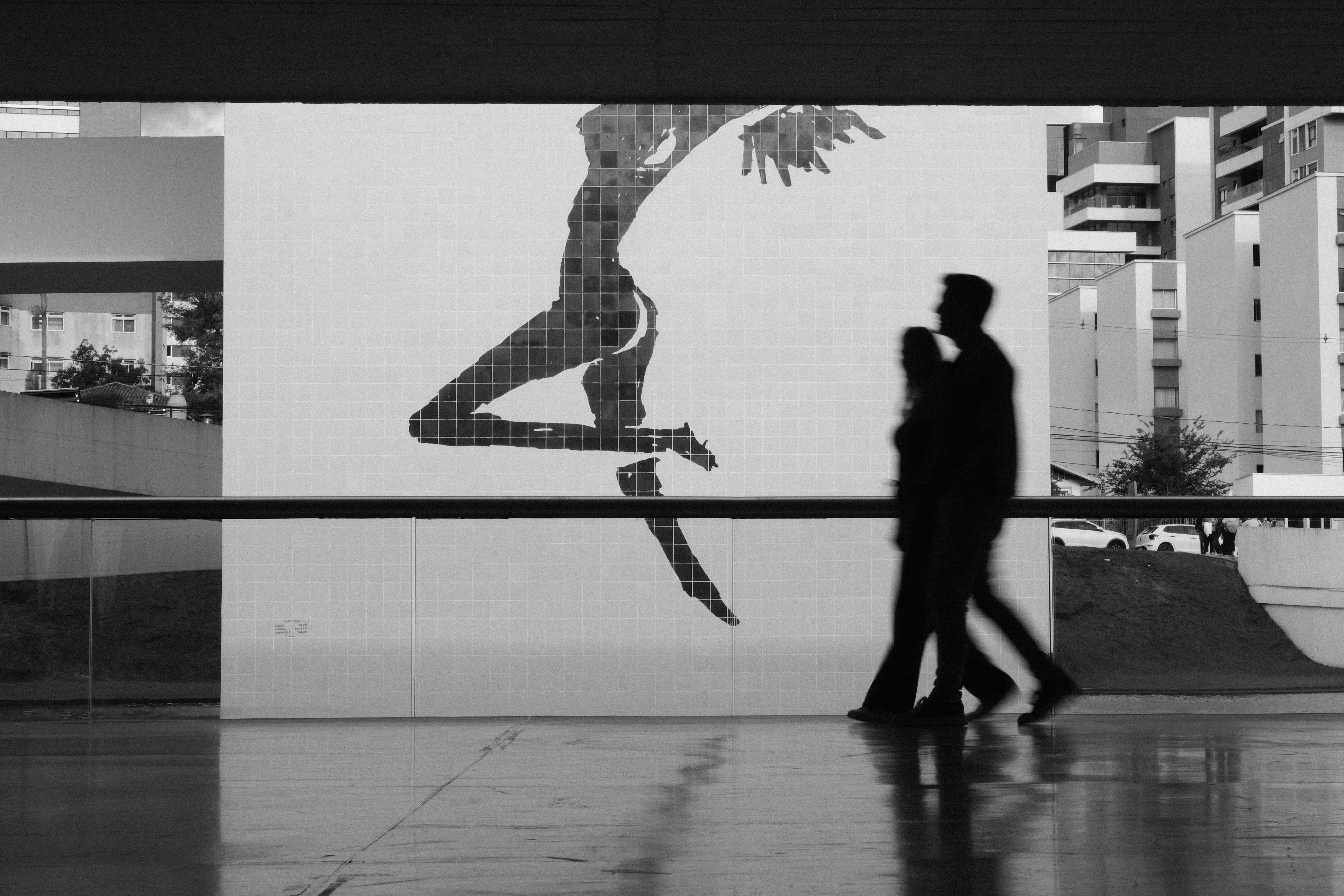 Silhouettes of a couple walking past a mural.