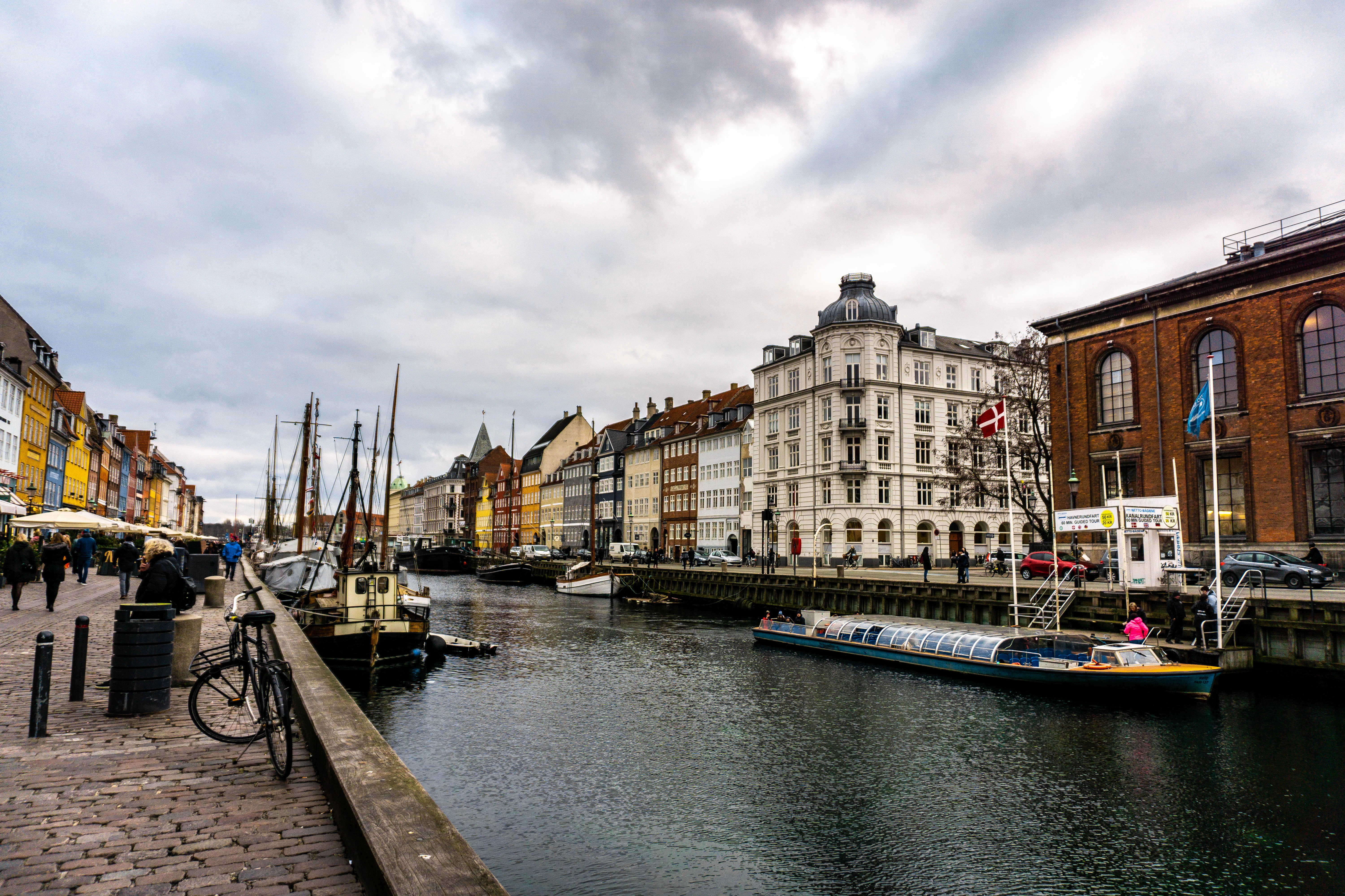 boats on body of water viewing multicolored buildings under white and gray sky during daytime