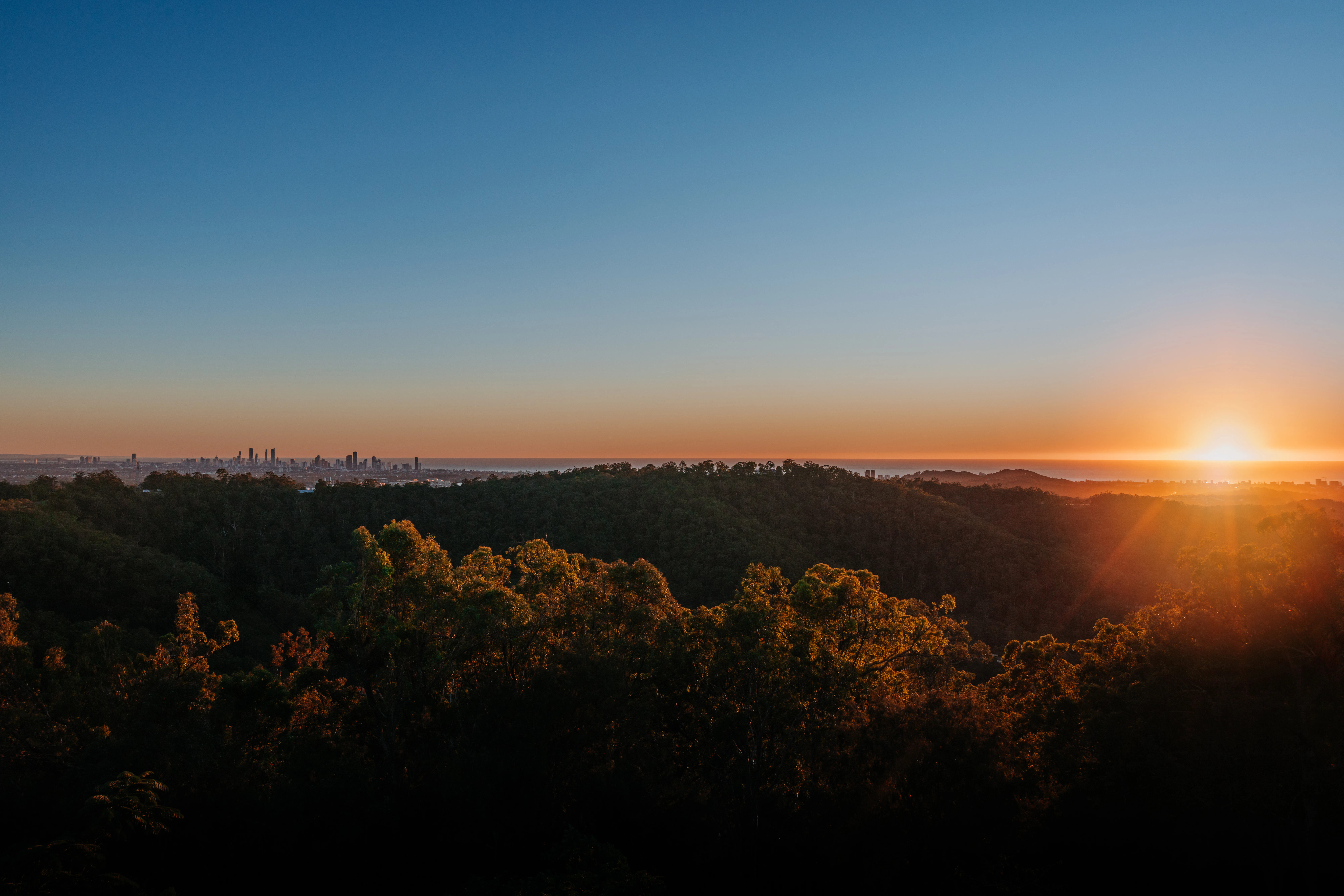 Sunrise over a distant city skyline and hills.