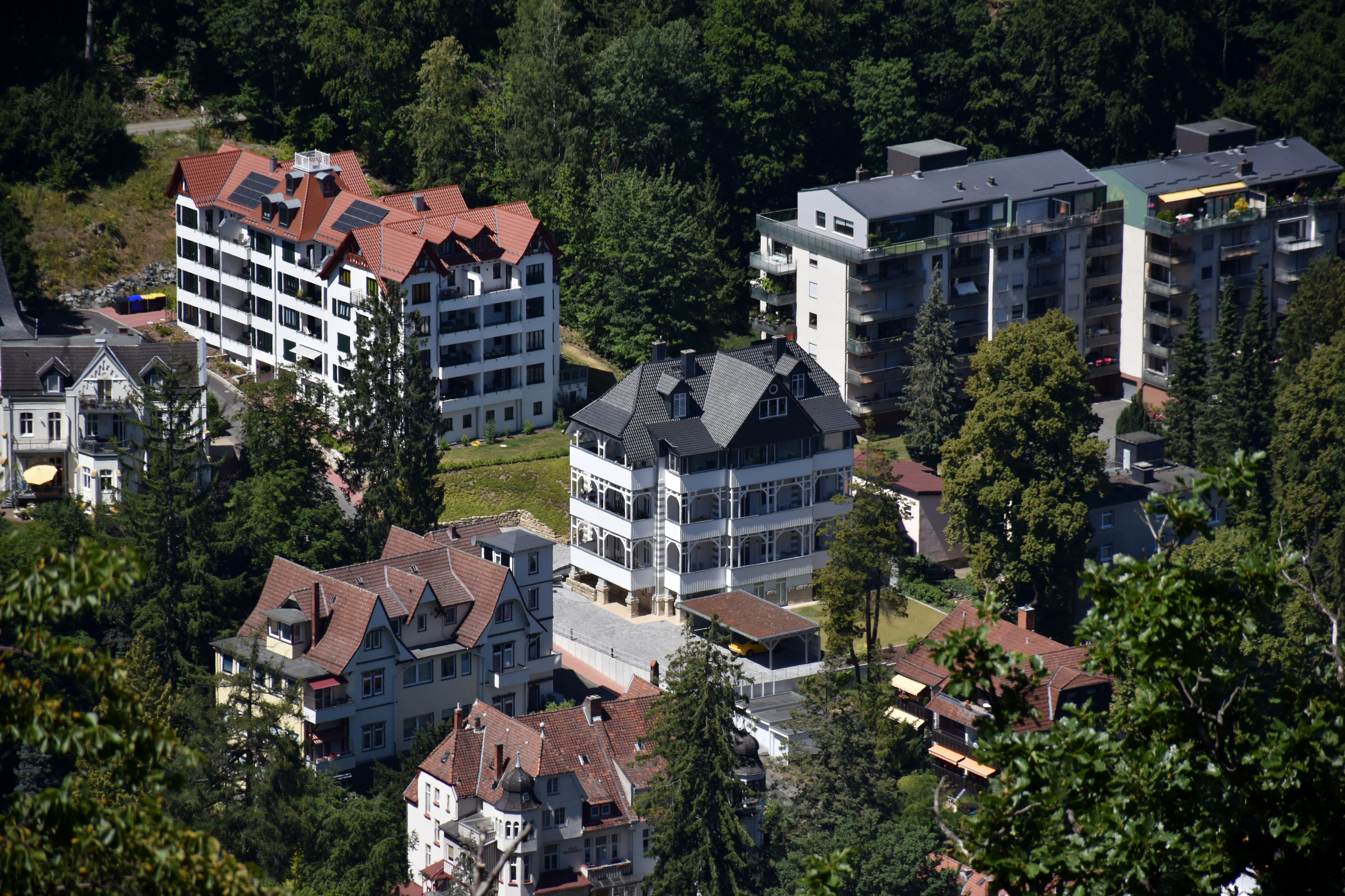 Buildings nestled among green trees on a sunny day.