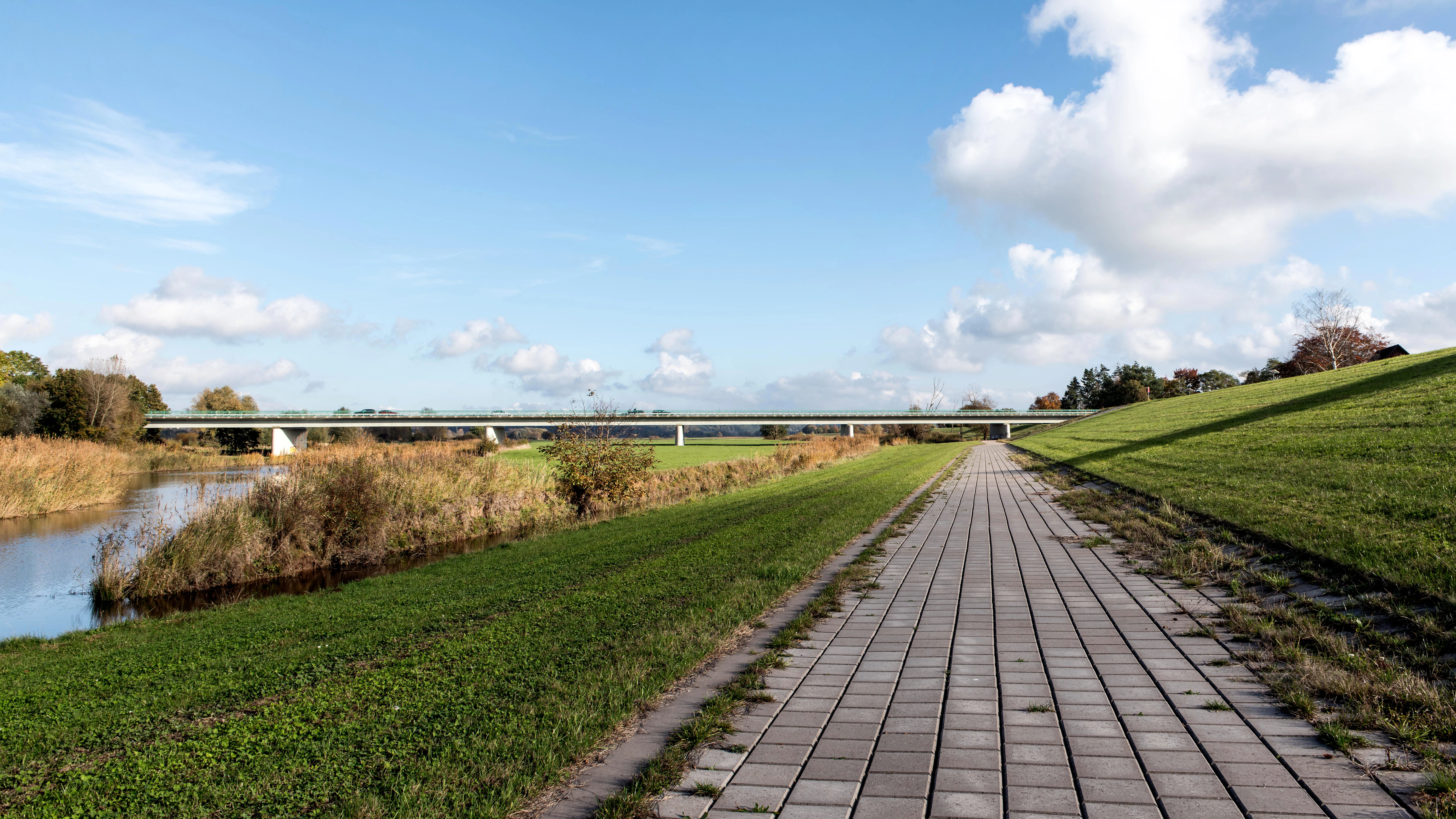Paved path beside a river and grassy embankment