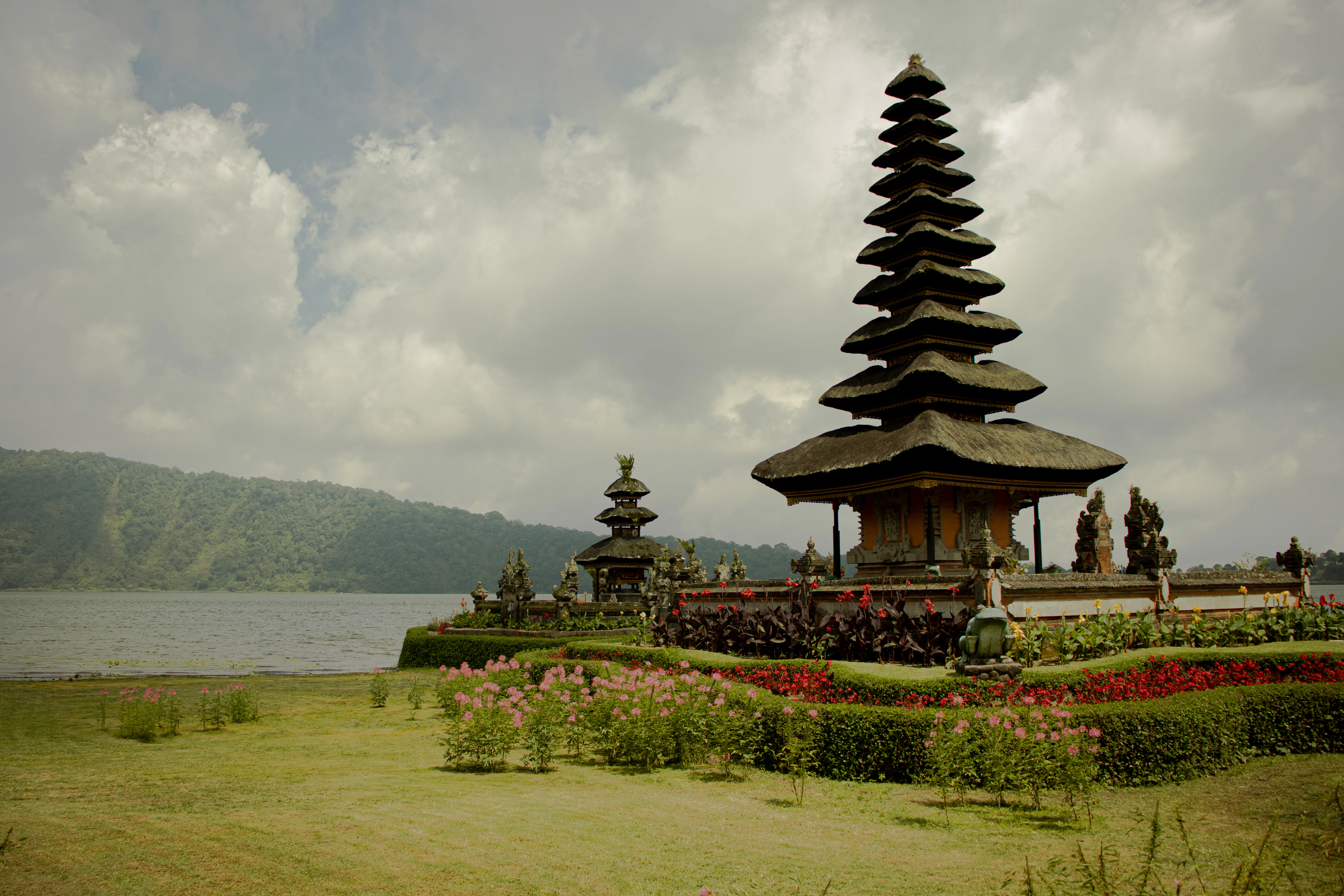 brown and black temple near green grass field and body of water under white clouds during
