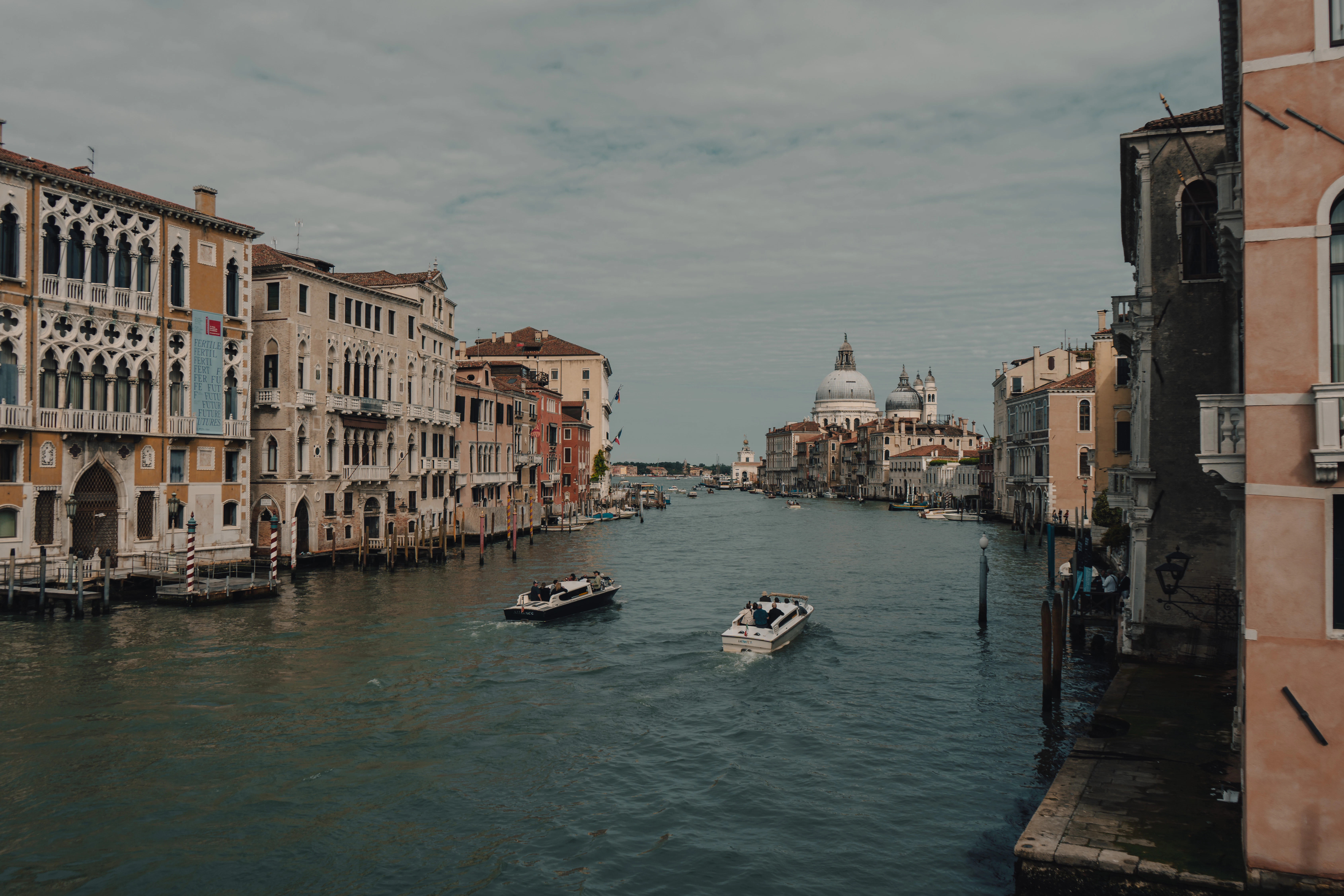 a couple of boats floating down a river next to tall buildings