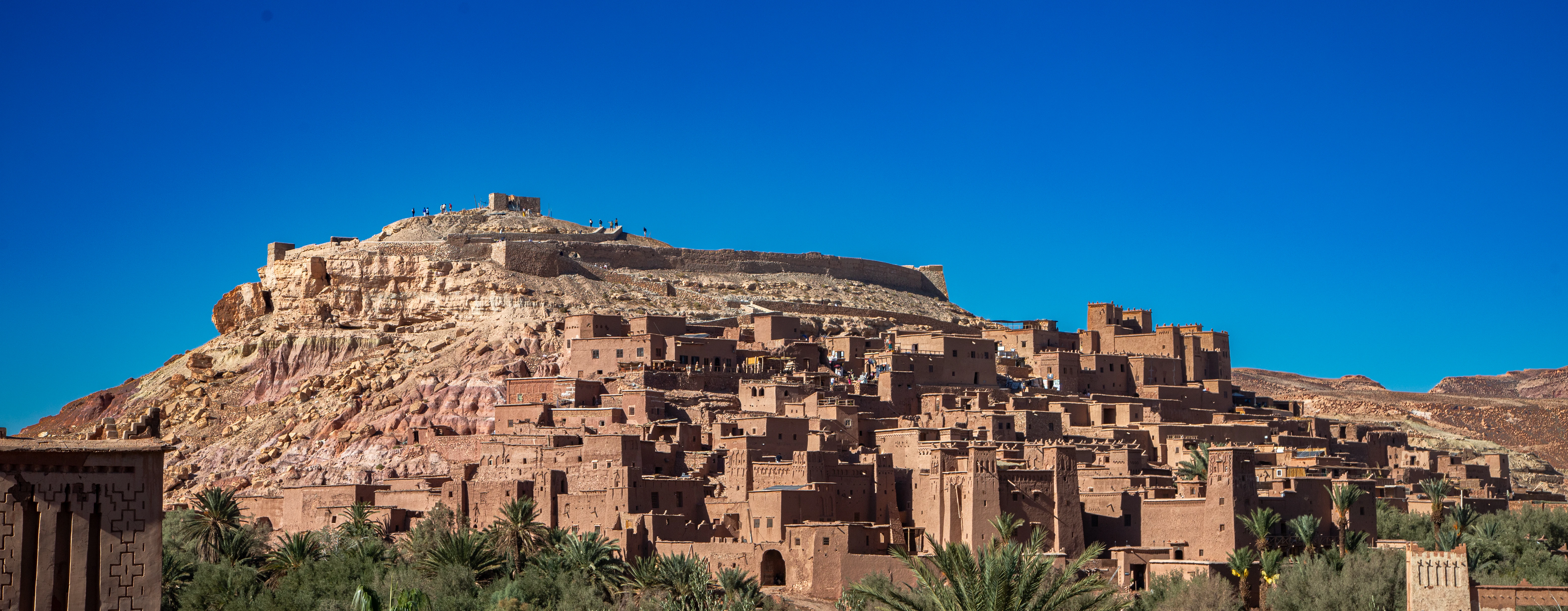 Ancient clay buildings on a hillside under blue sky