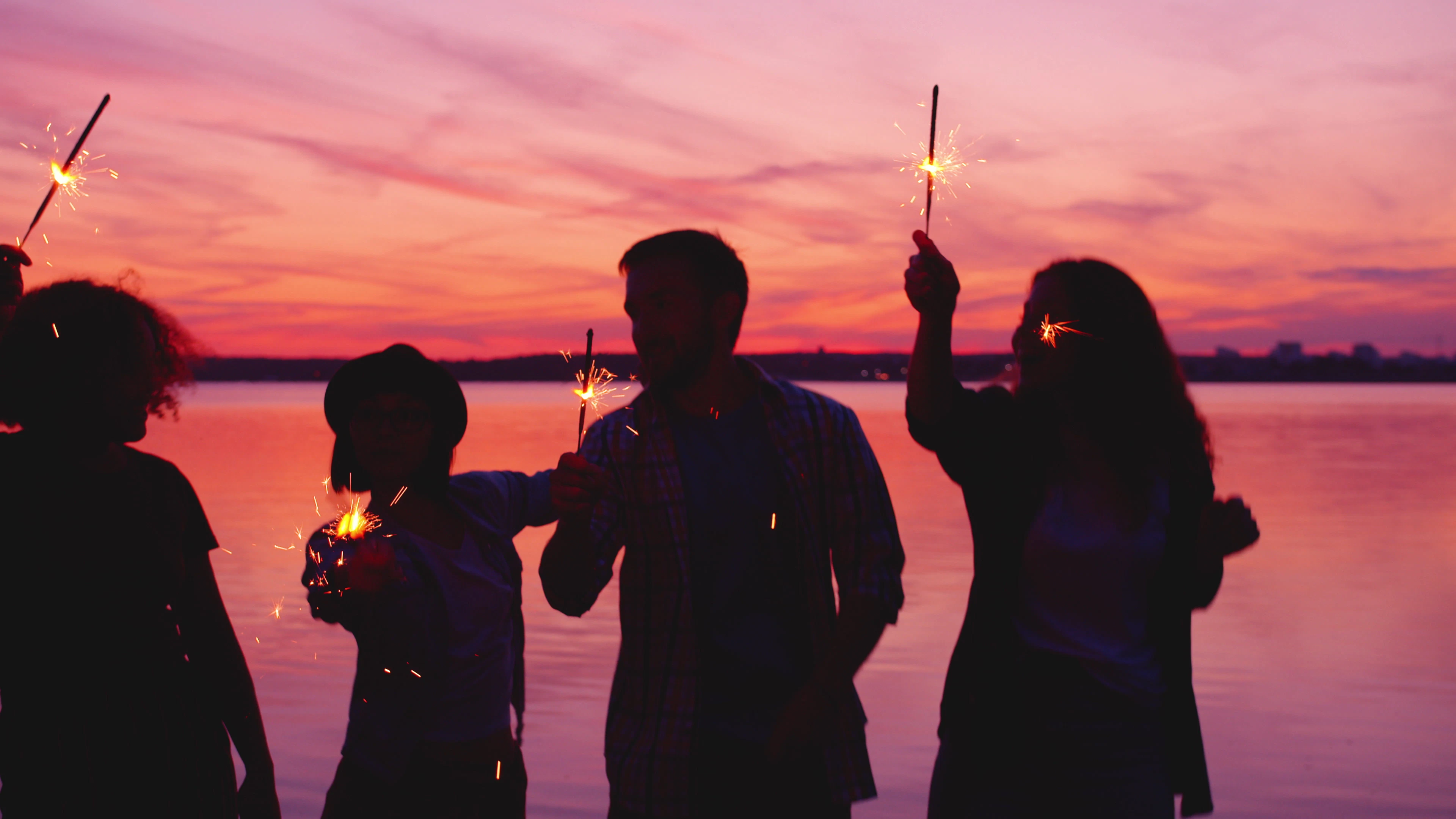 Family silhouetted against sunset with sparklers