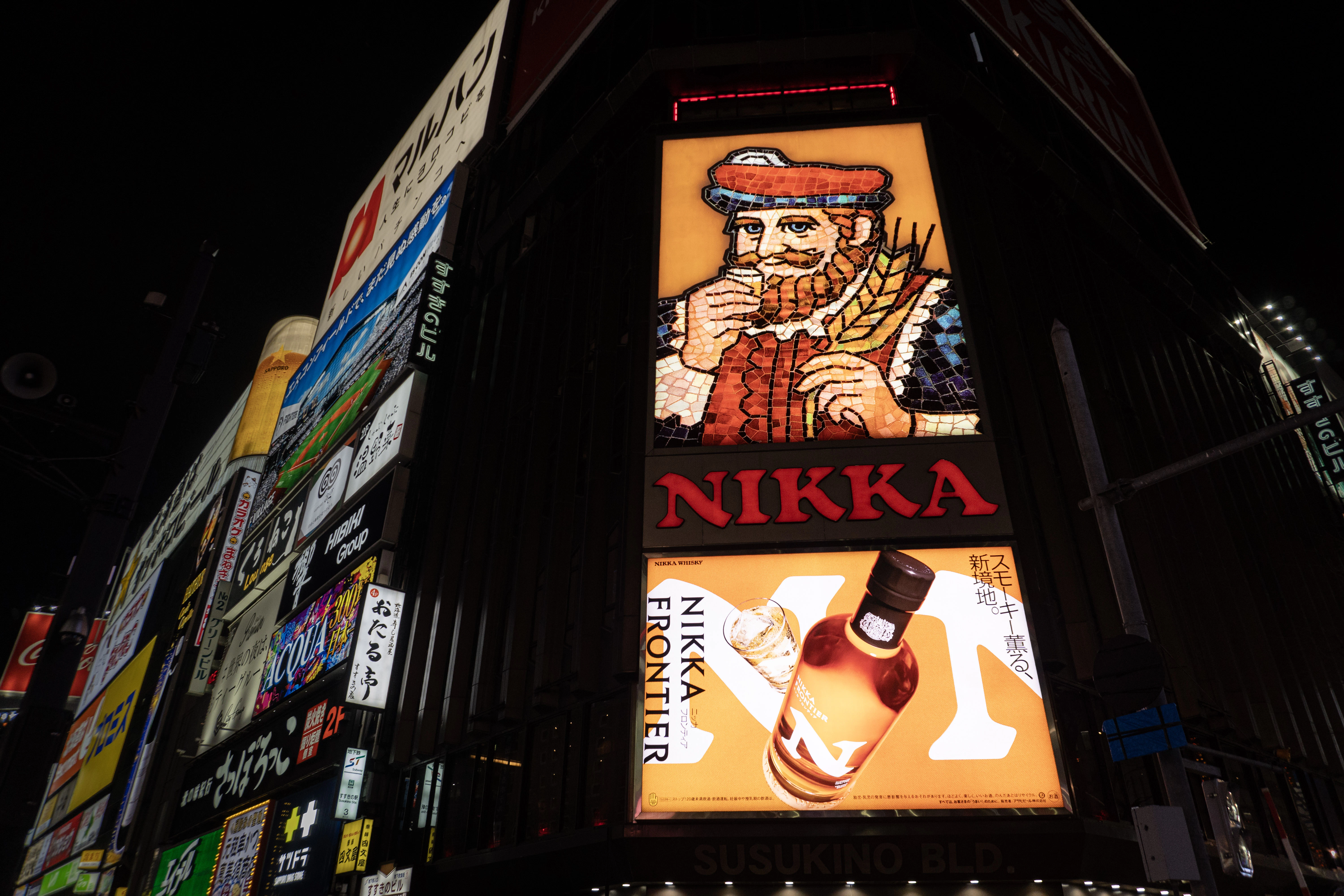 A neon nikka whiskey advertisement glows brightly at night.