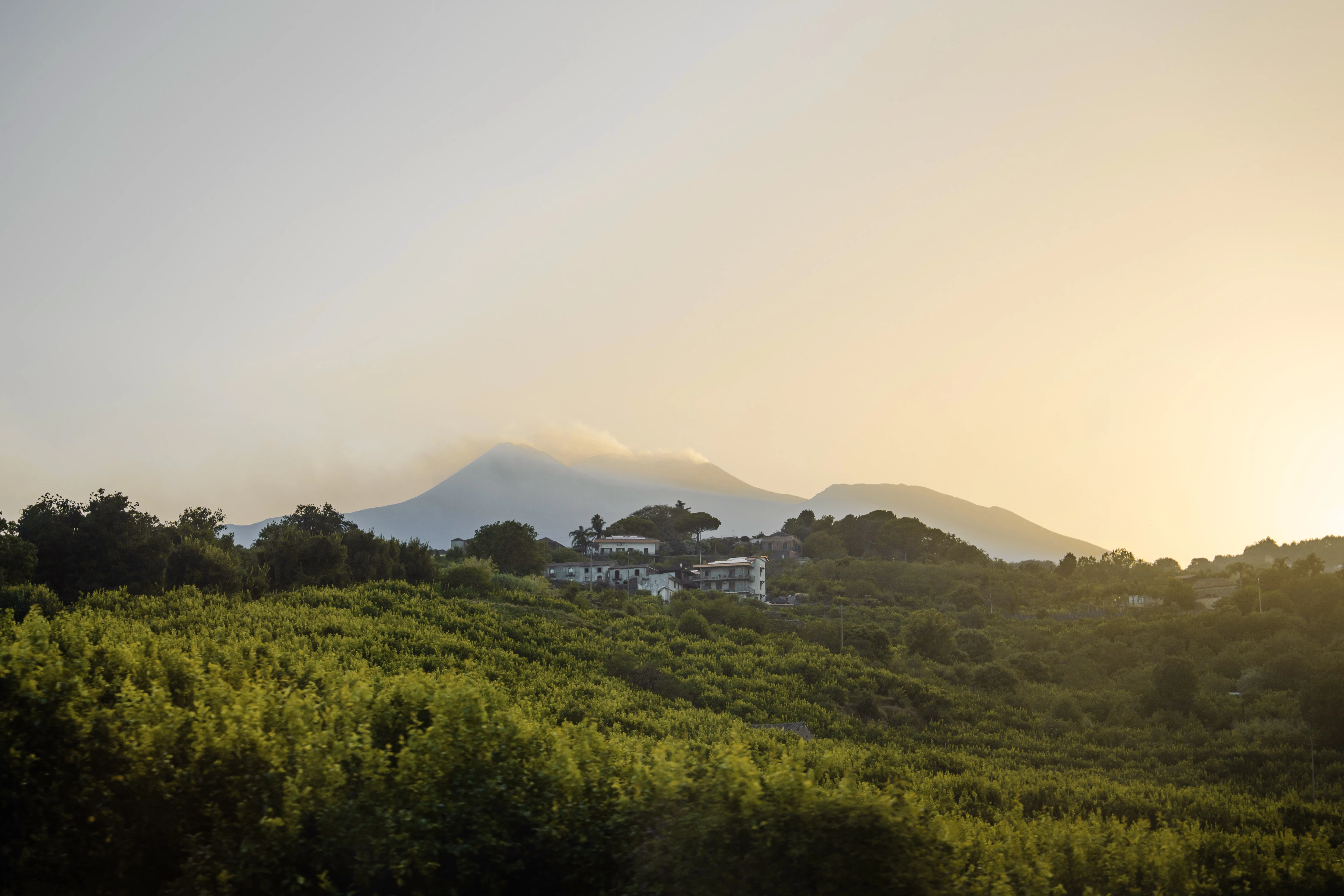 Sunset over the mountains with a building.