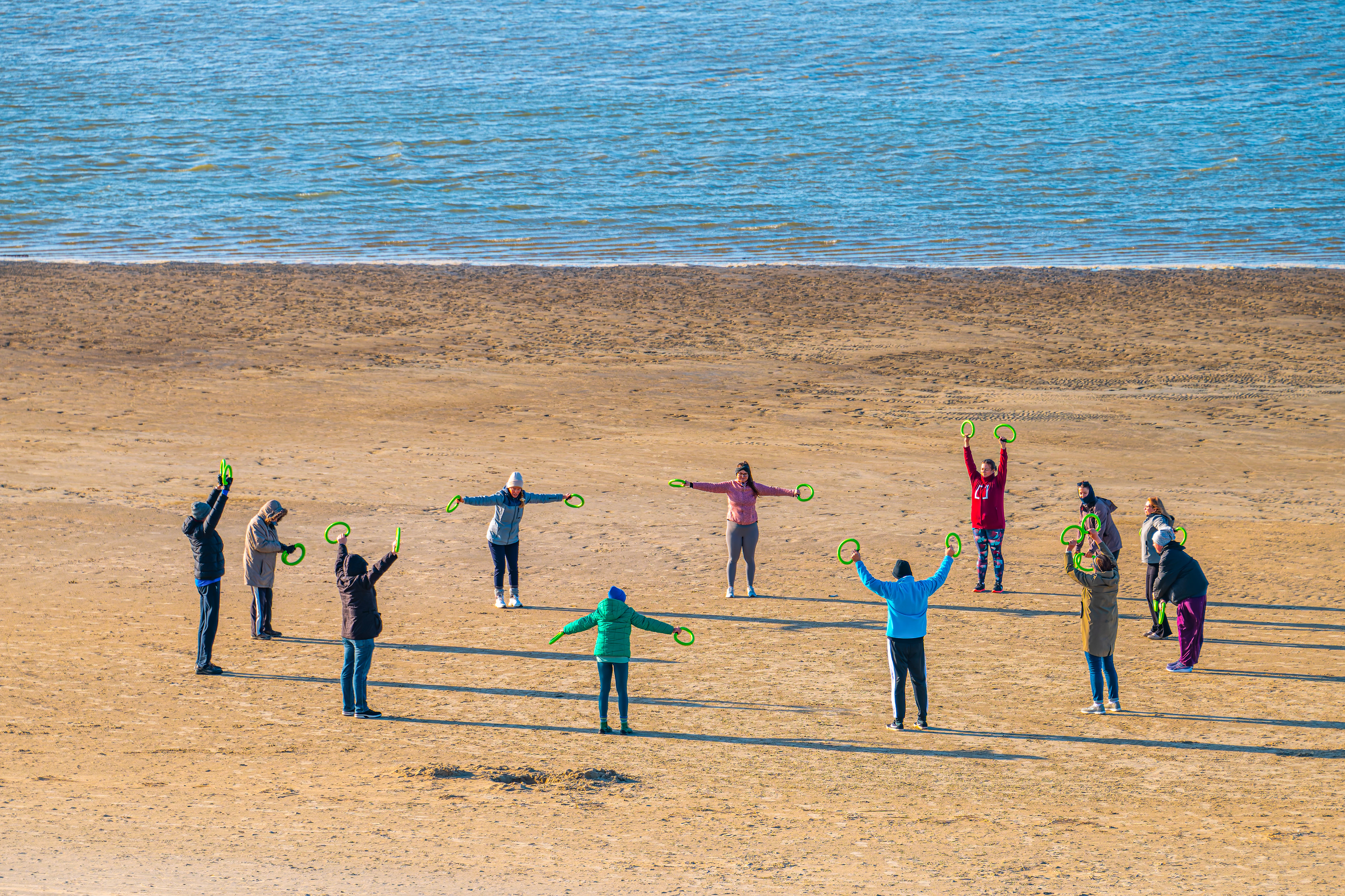People exercising in a circle on a sandy beach.