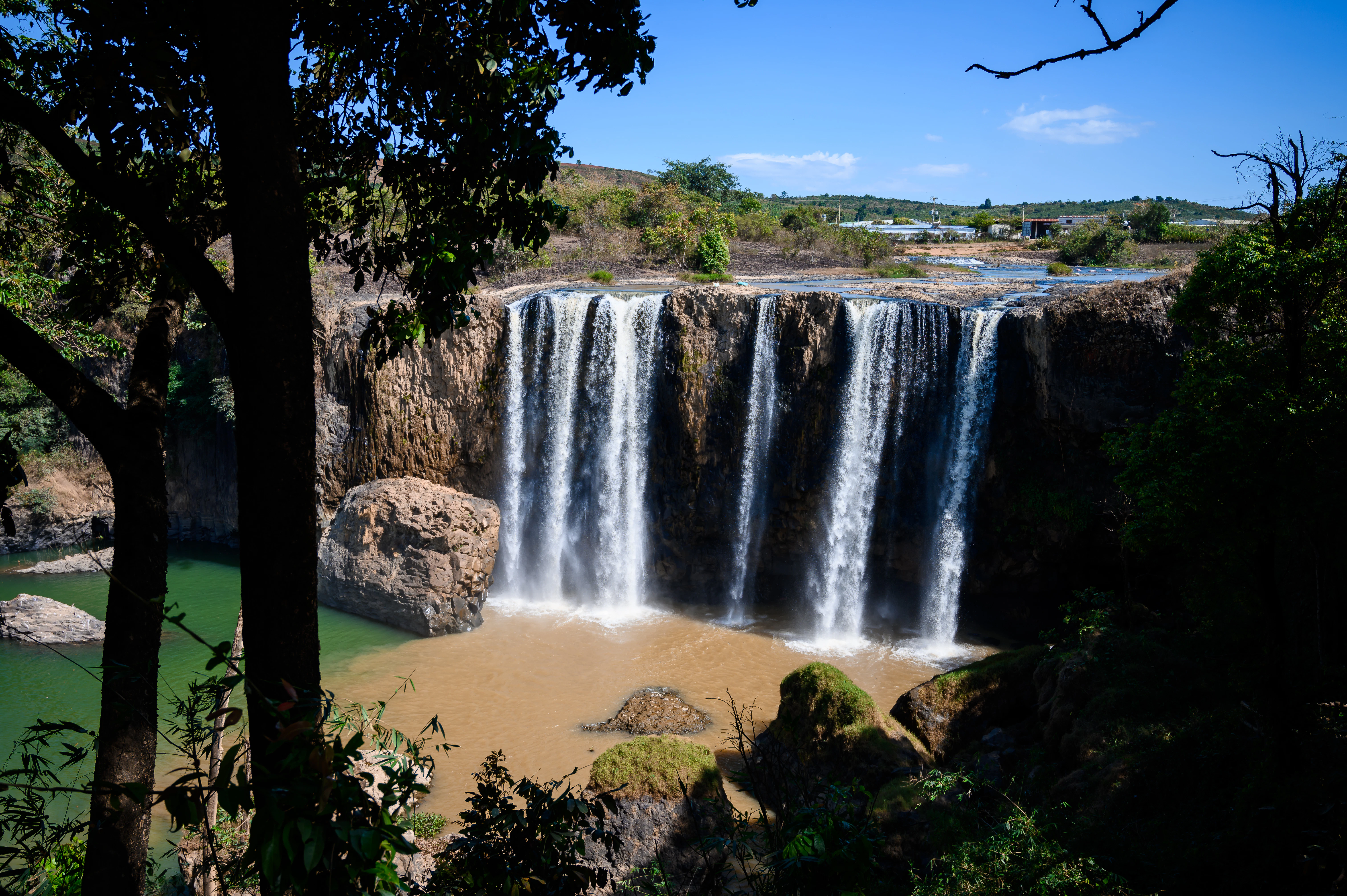 a large waterfall with a body of water in front of it