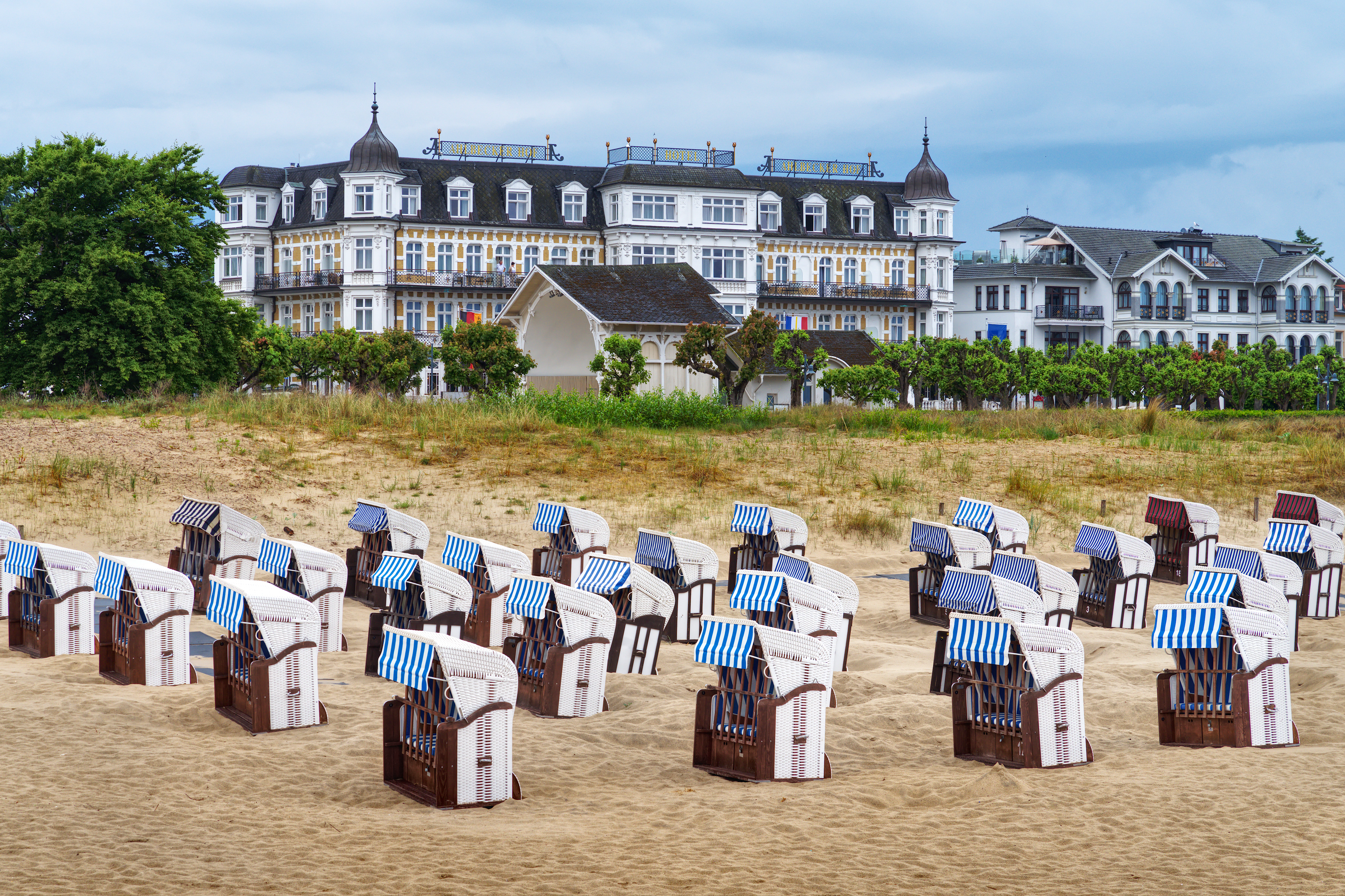 Beach chairs on sand with historic buildings behind.