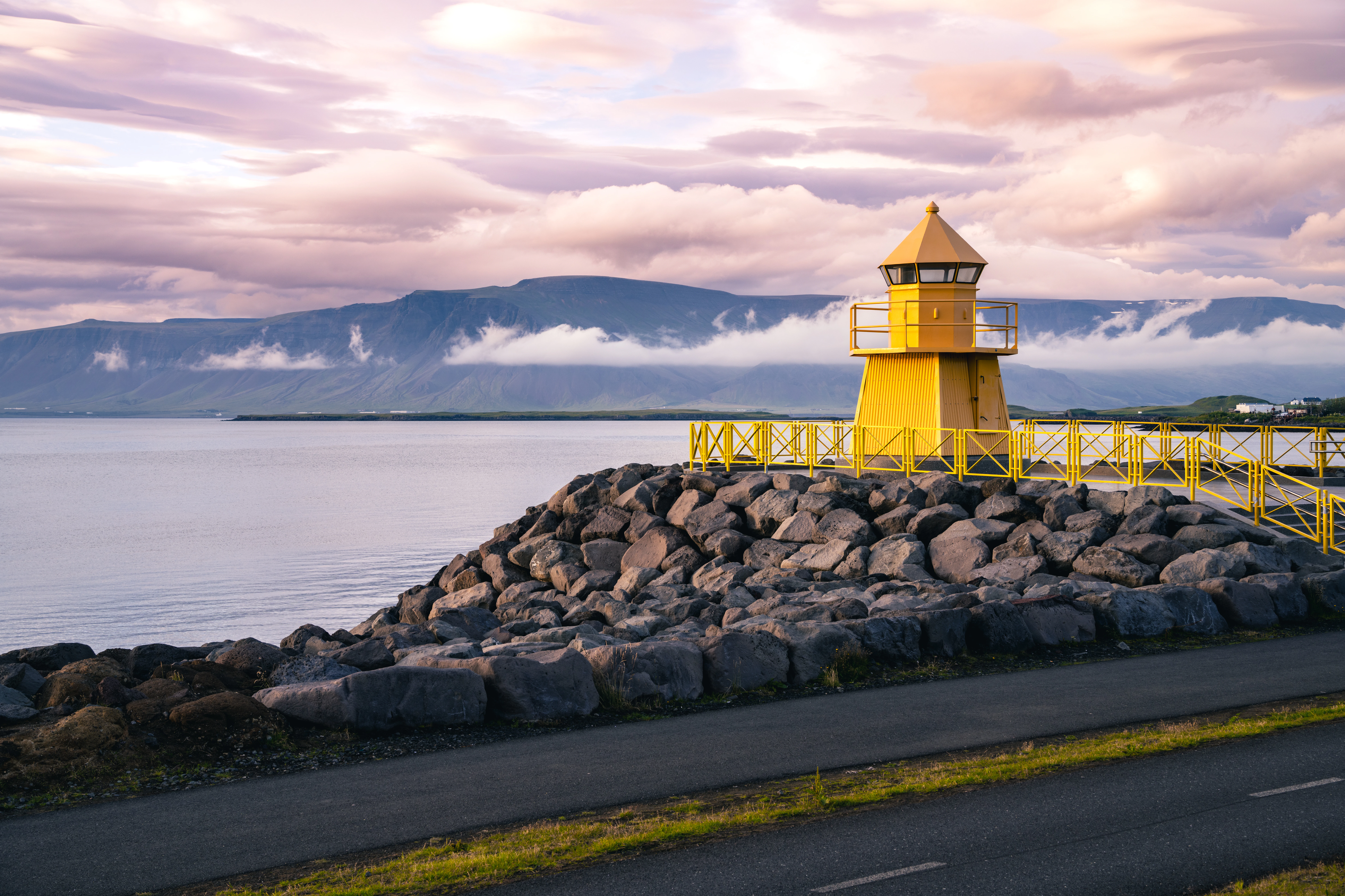 A yellow lighthouse sitting on top of a rocky shore