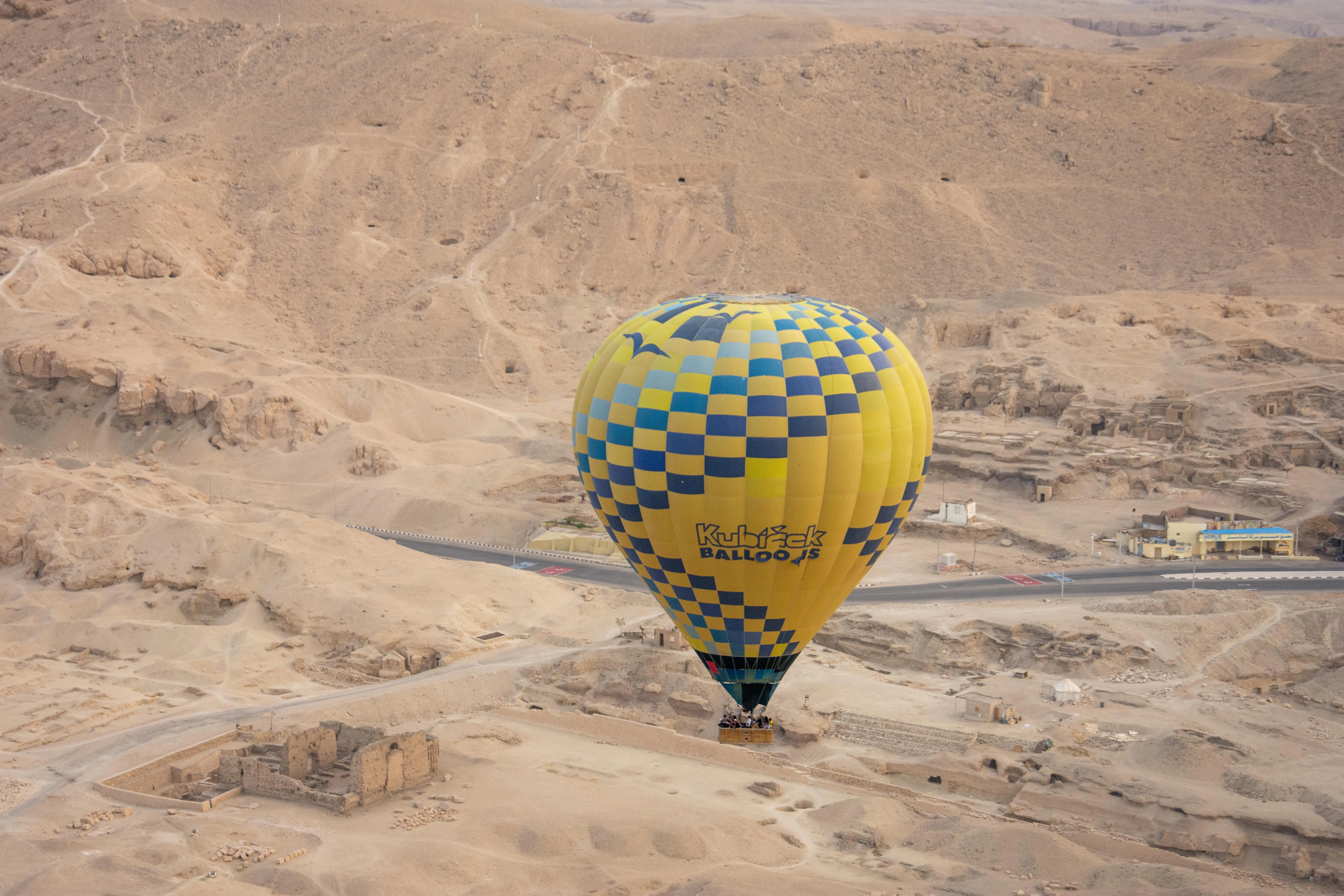 A hot air balloon flies over a desert landscape.