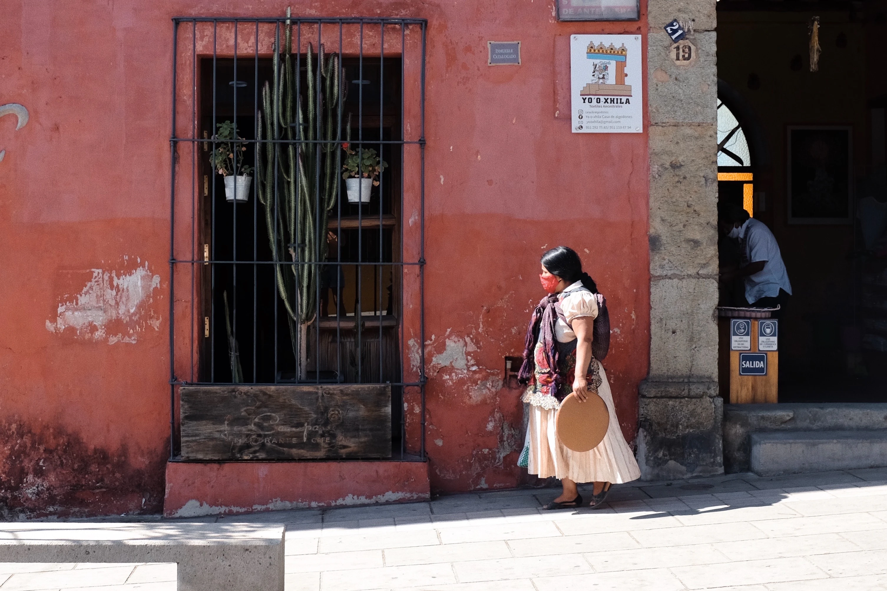 a woman walking down a street past a red building