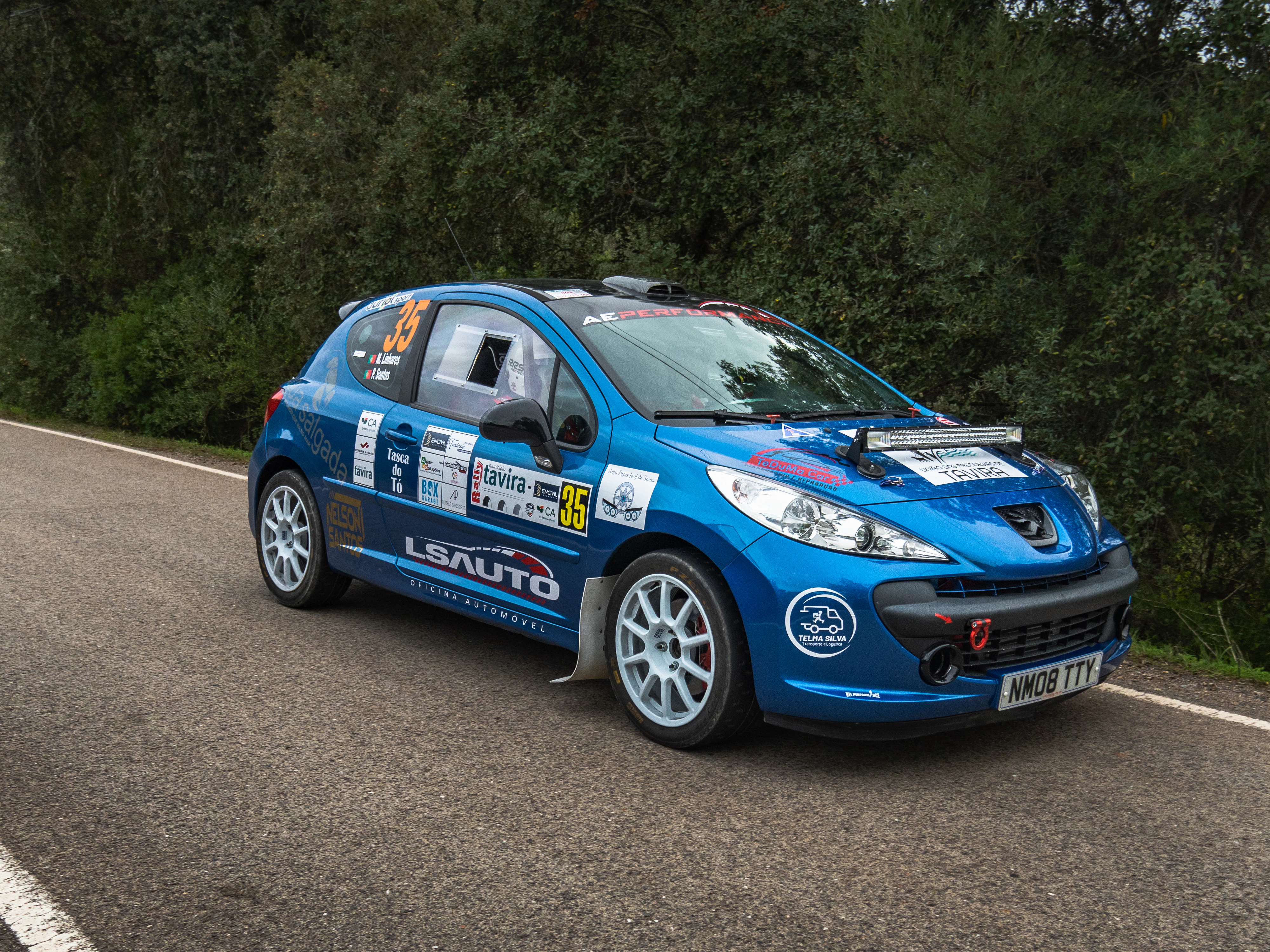 Blue rally car driving on a paved road