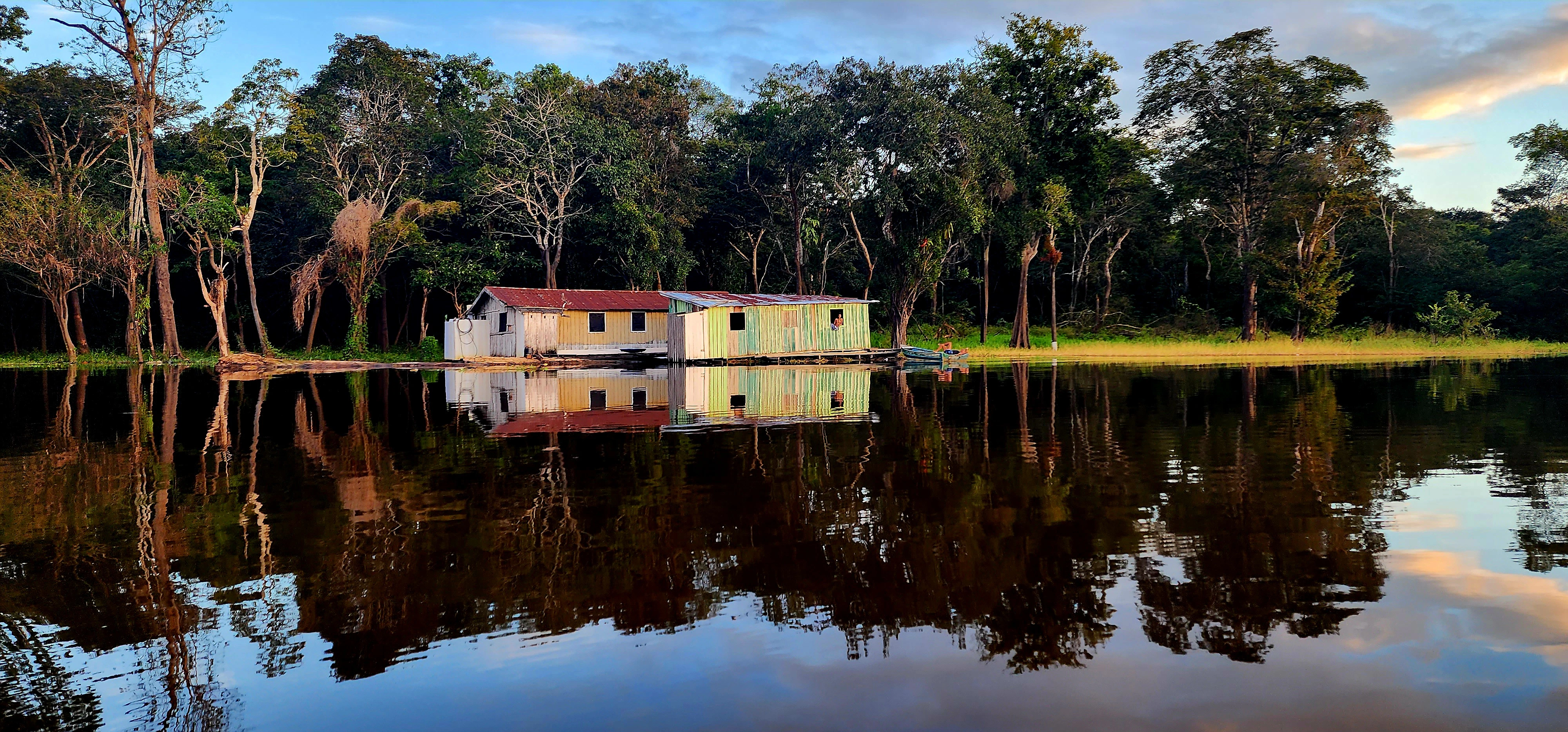 a house sitting on top of a lake next to a forest