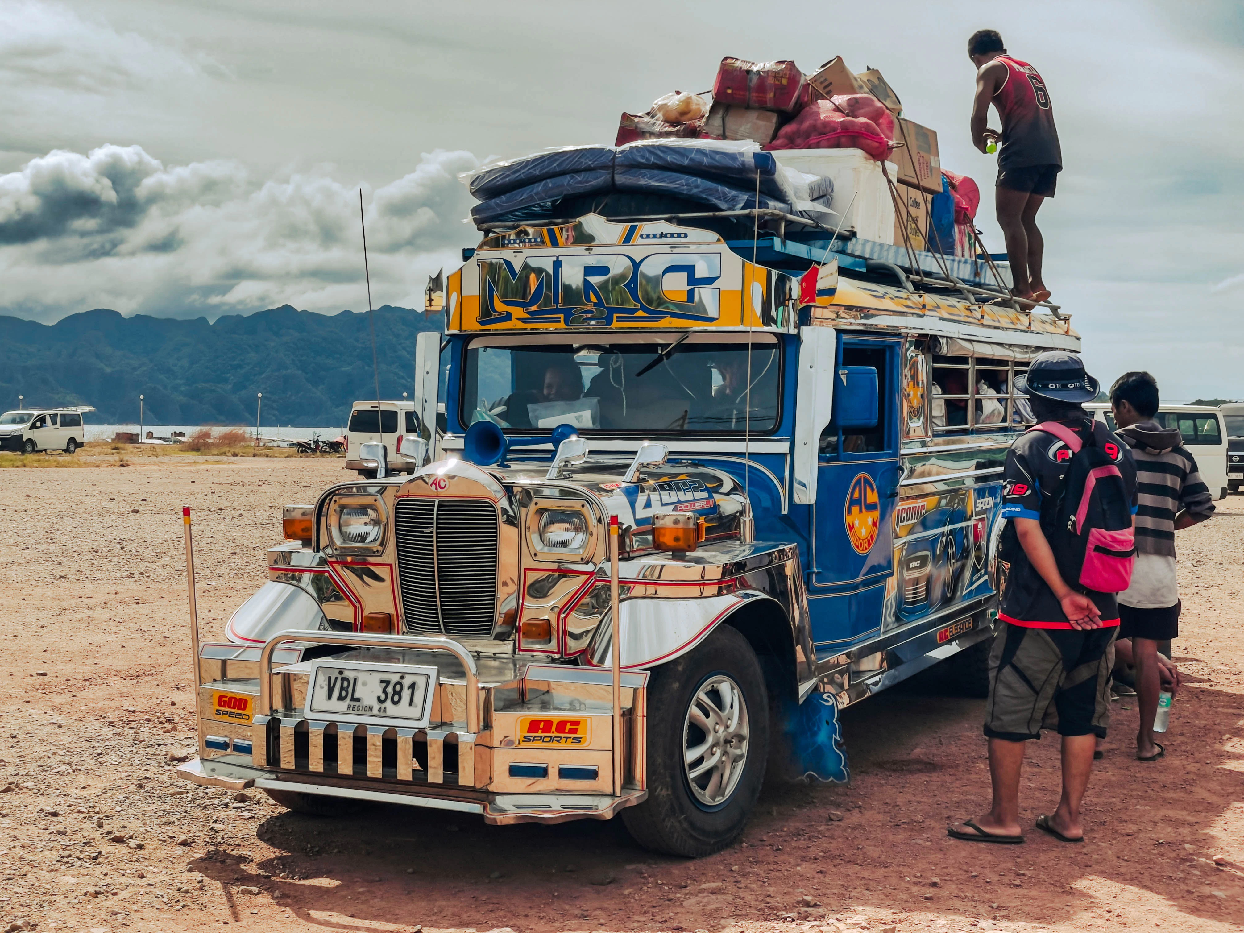 A colorful jeepney overloaded with luggage and people.