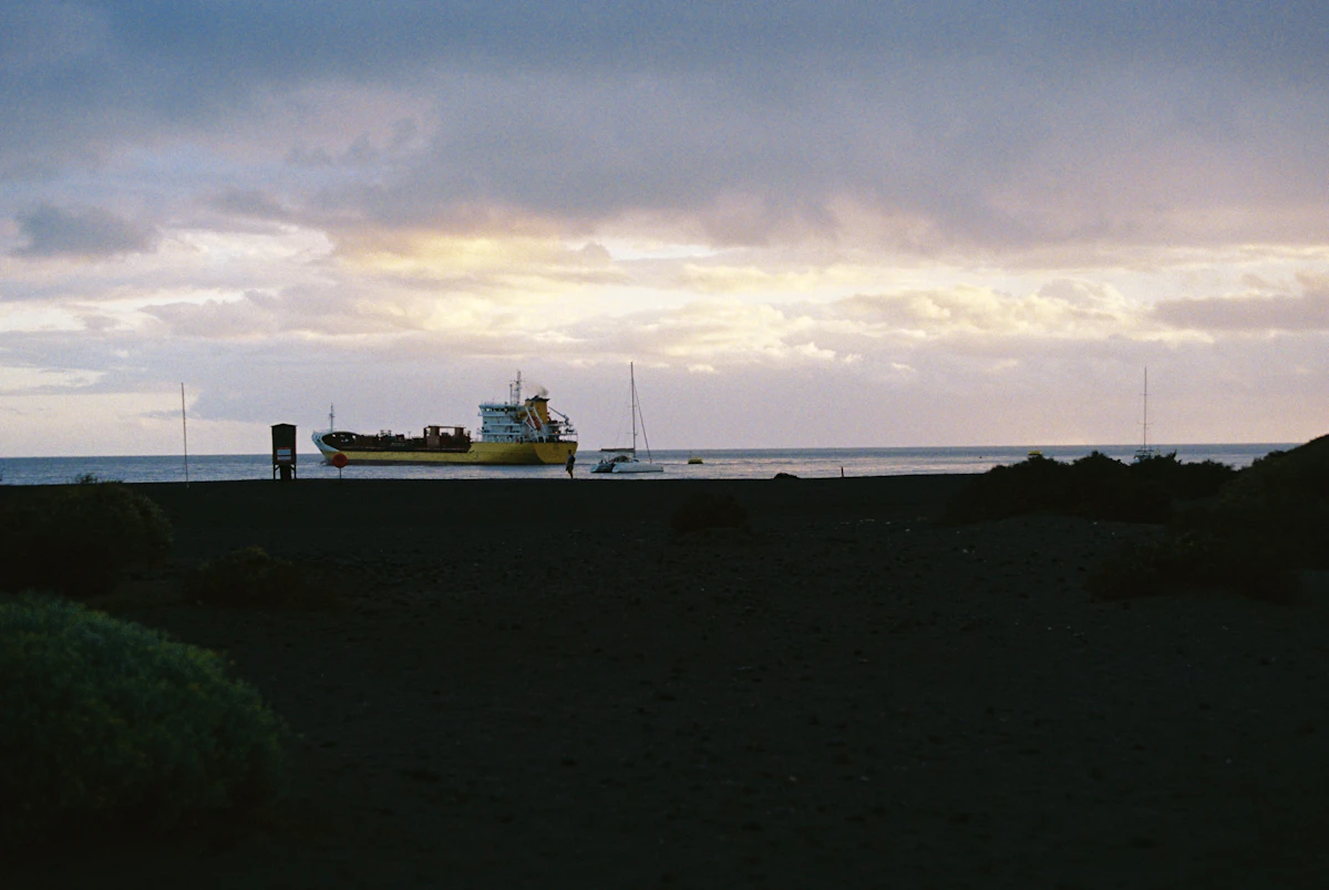 A boat sitting on top of a beach under a cloudy sky