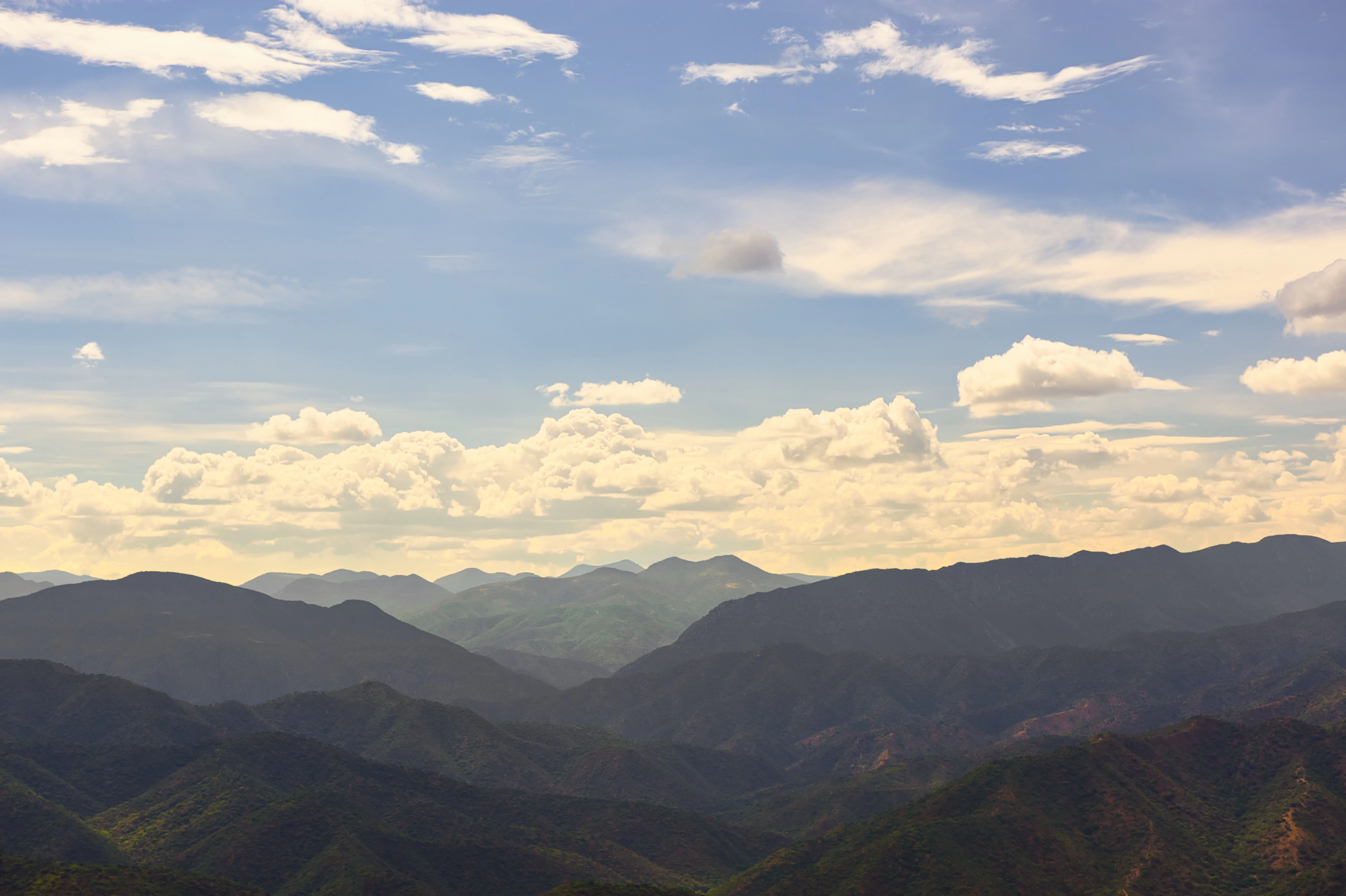 Rolling mountains under a cloudy blue sky