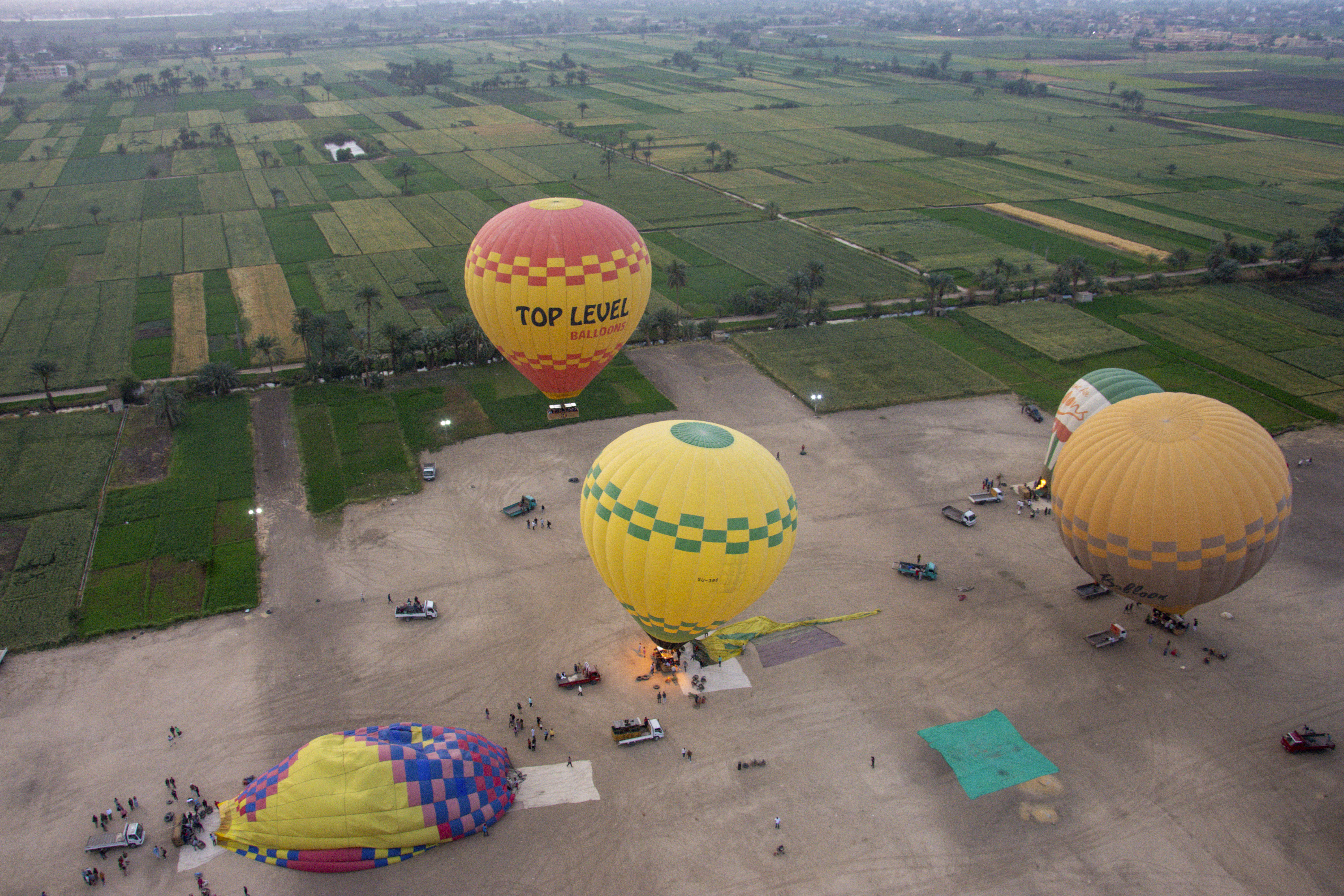 Hot air balloons preparing for flight over fields.